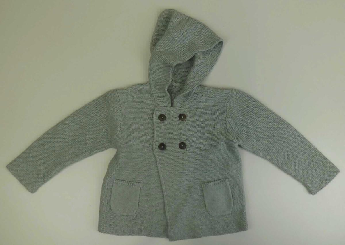 Strickjackenähnliches Kleidungsstück  sog. Baby Jäckchen mit Kapuze, in Kleinkindergröße, Foto siehe Anlage,
- aus ca. 2 mm dicken, einfarbigen Gewirken, aus laut Antrag 80 % Baumwolle und 20 % Seide, 
- über die Taille reichend (Rückenlänge: 33 cm),
- mit angearbeiteter Kapuze,
- vorn mit einer durchgehenden Öffnung mit Knopfverschluss von links auf rechts, 
- mit langen Ärmeln, 
- mit zwei aufgesetzten, offenen Taschen unterhalb der Taille, 
- am unteren Rand und an den Ärmelenden abgepasst gewirkt,
- ist für Kleinkinder mit einer Körpergröße von bis zu 86 cm bestimmt,
- weist weder aufgrund der Ausstattung (ungefüttert) noch des Schnitts (nicht in Bahnen gearbeitet) eine
  Formfestigkeit auf, somit keine Jacke.

"Kleidung (Strickjackenähnliches Kleidungsstück), aus Gewirken, für Kleinkinder, aus Baumwolle"