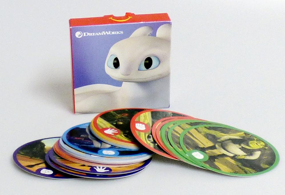 Gesellschaftsspiel in Form eines Kartenspiels, sog. "Mc Donald´s – Dreamworks Allstars - 2022", hier "3-in-1 All-Stars Classic Games":

- mit 32 runden Karten aus dünner Pappe,
- mit einem Durchmesser von ca. 8 cm,
- auf der Rückseite einheitlich mit einem Filmlogo bedruckt,
- auf der Vorderseite mit den Abbildungen von verschiedenen Filmcharakteren
  (4x je gleich) und kleinen Symbolen (Schere,Stein oder Papier) versehen,
- mit einer Anleitung in einer bunt bedruckten Pappschachtel für den
  Einzelverkauf aufgemacht.

Laut Anleitung kann mit den Karten auf drei verschiedene Arten gespielt werden:

1. als "Snap"
Hier werden die Karten gleichmäßig an alle Spieler verdeckt verteilt. Der erste Spieler deckt die oberste Karte seines Stapels auf und legt ihn in die Mitte. Der nächste Spieler deckt seine oberste Karte auf und legt sie auf den Stapel. Passen die Karten zusammen, ruft der Spieler, der dies zuerst entdeckt "Snap" und bekommt den Stapel. Es wird gespielt, bis kein Mitspieler mehr Karten vor sich liegen hat. Sieger ist derjenige, der die meisten Karten vom Stapel gesammelt hat.

2. als "Memory"
Hier werden die Karten verdeckt auf den Tisch gelegt. Reihum decken die Spieler zwei Karten auf. Passen sie zusammen, darf der Spieler sie behalten, sonst werden sie wieder umgedreht. Sieger ist der Spieler mit den meisten Kartenpaaren.

3. als "Schere-Stein-Papier"
Hier werden die Karten gleichmäßig auf zwei Spieler verdeckt verteilt. Jeder Spieler deckt seine oberste Karte auf. Es werden die kleinen Symbole nach den Regeln des Kinderspiels "Schere-Stein-Papier" verglichen. Der Sieger des Vergleichs bekommt die beiden Karten. Wer zuerst alle Karten für sich gewinnt, gewinnt auch das Spiel.

Die Ware ist zolltarifrechtlich als "Gesellschaftsspiel, Spielkarten" einzureihen.