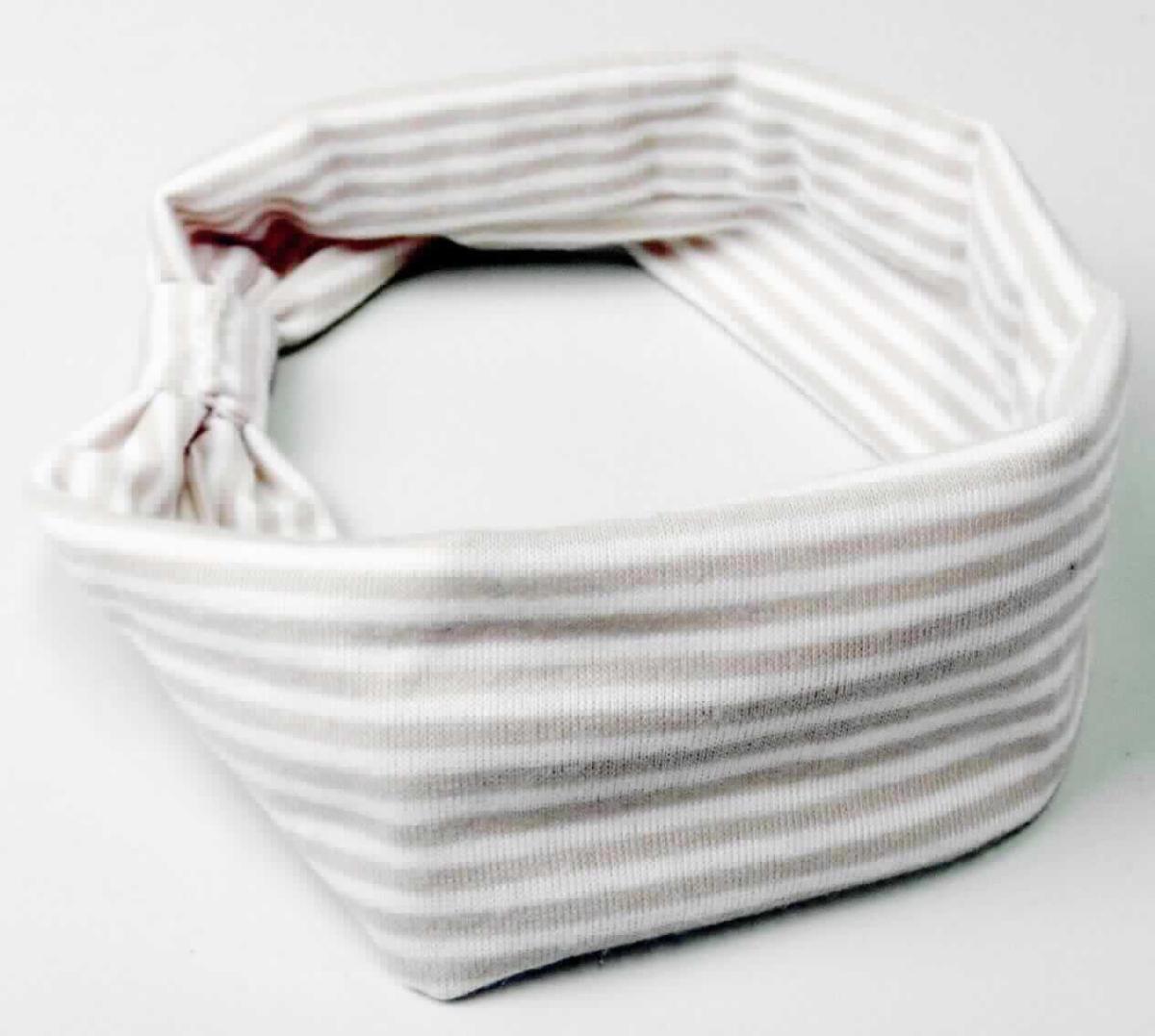 Kopfband, sog. Haarband Schleifen-Optik, LAN 11630, Foto siehe Anlage,
- an einem bedrucktem Kunststoffaufhänger befestigt,
- mit einem Umfang von ca. 40 cm und einer Breite (flachliegend) von ca. 4,5 cm,
- aus ca. 0,7 mm dicken, buntgewirkten Gewirken aus laut Antrag 95 % Baumwolle und 5 % Elasthan 
  (synthetische Chemiefasern); weder gummielastisch noch kautschutiert,
- durch schlauch- und ringförmiges Zusammennähen konfektioniert,   
- vorn mit einem um die Nahtstelle geführten, ca. 2,5 cm breiten "Ring" aus den den o. g. Gewirken und 
  dadurch gerafft,
- wird üblicherweise als Kopfband/Haarband zum Zurückhalten des Haares getragen, 
- in Anbetracht des textilen Charakters wird die Ware nicht vom Warenkreis der Position 9615 erfasst,
- individuelles (selbstständiges) Einzelstück, das eine Ergänzung von Kleidung darstellt.

"Anderes konfektioniertes Bekleidungszubehör (Kopfband), aus (weder gummielastischen noch 
 kautschutierten) Gewirken"