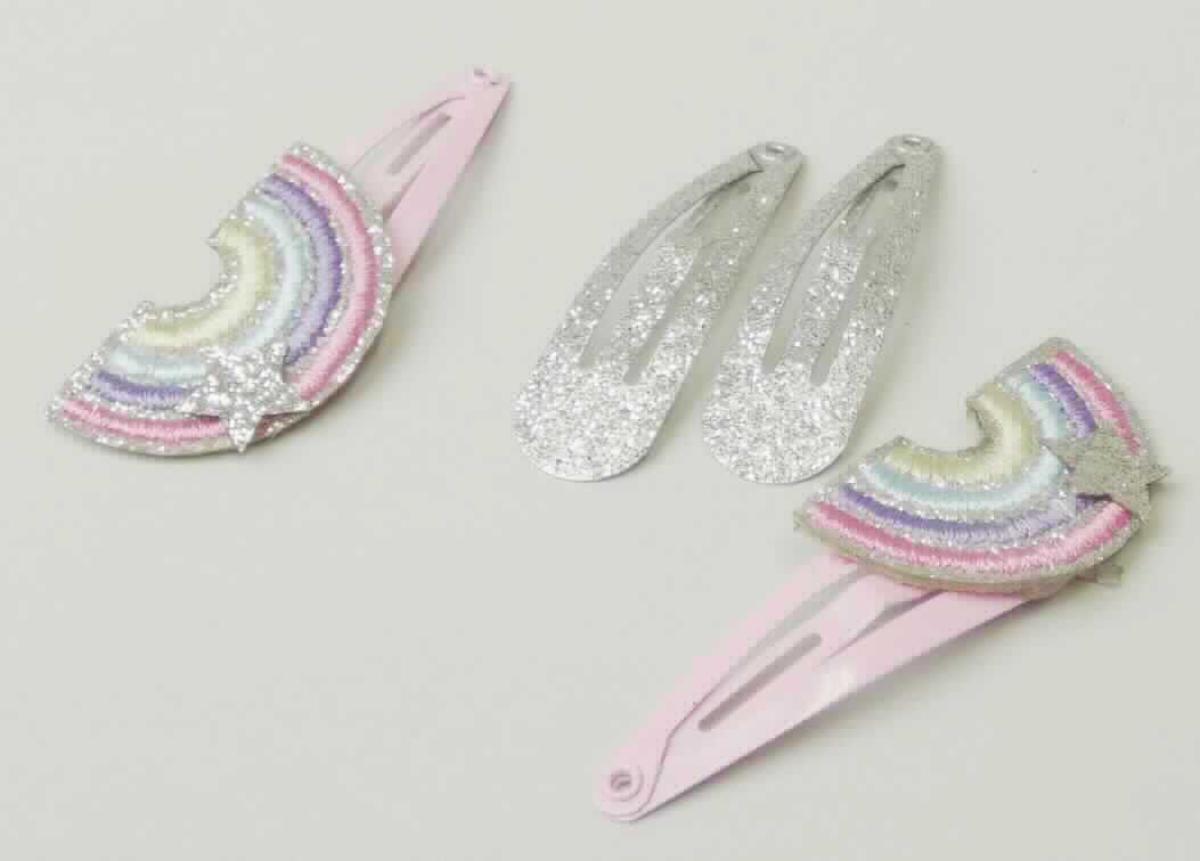 Bei dem sog. "Haarclips, LAN 11644" handelt es sich um ein Set bestehend aus:
- zwei ca. 4 cm langen, tropfenförmigen und auf Spannung gebogenen, silberfarbenen Metallspangen, die mit einem silberfarbenen Glitzer bedeckt sind,
- zwei ca. 4 cm langen, tropfenförmigen und auf Spannung gebogenen, rosafarbenen Metallspangen (charakterverleihend im Hinblick auf die Verwendung), auf die ein Regenbogenmotiv aus Spinn- bzw. Kunststoff aufgeklebt ist. 

Die Waren dienen dem Zusammenhalten des Haares und sind auf einem Pappkarton in einer Kunststofftüte aufgemacht. 

Das Set ist als "Haarspangen aus unedlem Metall" einzureihen.