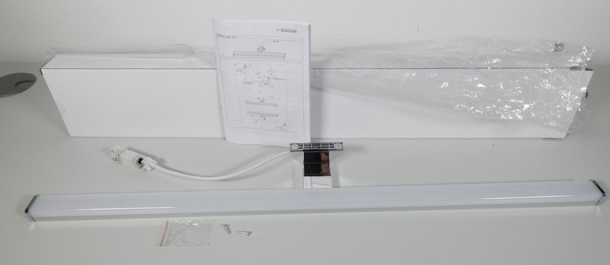 Bei der Ware (Abbildung siehe Anlage) handelt es sich um einen ca. 780 mm x 98 mm x 44 mm (L x B x H) großen elektrischen Beleuchtungskörper, im Wesentlichen bestehend aus einem rechteckigen u-förmigen Metallgehäuse mit einer weißen rechteckigen u-förmigen transparenten Kunststoffabdeckung, Endkappen aus silberfarbenem Kunststoff, einer rechtwinkeligen Halterung mit Befestigungsvorrichtung aus Kunststoff, integriertem LED-Leuchtmittel und elektrischer Ausstattung (u. a. Kabel mit Anschlussbox). Das Erzeugnis ist dazu bestimmt, direkt an den elektrischen Strom angeschlossen zu werden.
Es dient der Innenbeleuchtung und ist dazu vorgesehen, an einem Schrank oder einem Regal befestigt zu werden.

Im Hinblick auf das äußere Erscheinungsbild und die Bedeutung in Bezug auf die Verwendung (Kunststoff für Lichtlenkung und Stabilität; Metall für Form und Stabilität) ist der charakterbestimmende Stoff nicht ermittelbar. Hinsichtlich des Umfangs ist der Kunststoff charakterbestimmend.

Die Ware ist mit Montagematerial (zwei Schrauben) in einem Karton verpackt.

Das Erzeugnis ist als „elektrischer Beleuchtungskörper, anderweit weder genannt noch inbegriffen, nicht von den Unterpositionen (HS) 9405 11 bis 9405 41 erfasst, ausschließlich zur Verwendung mit LED-Lichtquellen bestimmt, kein Scheinwerfer, aus Kunststoffen“ einzureihen.