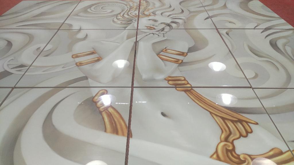 Ware aus Glas, sog. Glasplatte mit keramischem Untergrund, Foto siehe Anlage,
nach den Antragsangaben:
- in Form eines dekorativen Wandbelags,
- - aus einer Platte aus Glas,
- - - aus klarem, 1 mm dickem, feuerpoliertem Glas (Floatglas),
- - - mit geschliffenen Kanten,
- - - an der Rückseite mit einem Digitaldruck (Motiv) versehen und einem Schutzlack versiegelt,
- - aus einer Platte aus Keramik,
- - - aus Steinzeug,
- - - mit einer Dicke von 9 mm,
- - - vollständig auf die Rückseite der Glasplatte aufgeklebt,
- in unterschiedlichen Abmessungen: z. B. 30 cm x 60 cm und 60 cm x 60 cm,
- zur Verwendung als Wandbelag (z. B. in einer Dusche) bestimmt; mehrere Platten ergeben ein Motiv,
- keine Fliese der Position 7016, da nicht aus gepresstem oder geformtem Glas hergestellt,
- kein Druckerzeugnis des Kapitels 49, da der Zweck der Platte nicht nur durch den Druck bestimmt
  wird (stellt bei Verwendung als Wandbelag in der Dusche - über den Druck hinaus - einen Teil der 
  wasserdichten Außenwand der Dusche dar),
- die mit einem Motiv versehene Platte aus Glas bestimmt den Charakter der Ware im Hinblick auf
  das äußere Erscheinungsbild, die Platte aus Keramik überwiegt nach dem Umfang (Dicke); damit
  verleiht keiner der beiden Stoffe der zusammengesetzten Ware ihren wesentlichen Charakter, sie
  ist somit der von den gleichermaßen in Betracht kommenden Positionen (6907 und 7020) in der
  Nomenklatur zuletzt genannten Position zuzuweisen.

"Andere Ware aus Glas, andere als in den Unterpositionen 7020 0005 bis 7020 0008 genannte,
 aus anderem Glas als das in den Unterpositionen 7020 0010 bis 7020 0030 genannte"