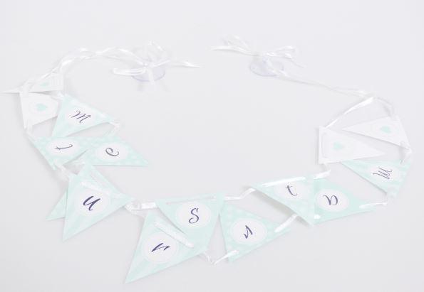 Nach den Angaben der Antragstellerin handelt es sich um eine sog. "Wimpelkette". Das Erzeugnis besteht aus dreieckigen Papierzuschnitten (Kantenlänge Oberseite 5 cm), die beidseitig mit Buchstaben oder Herzmotiven bedruckt sind. Die "Wimpel" sind auf zwei unterschiedlich lange Spinnstoffbändern aufgefädelt, welche an den Enden jeweils an einem Saugnapf verknotet sind.
Durch die Anordnung der bedruckten Wimpel, an den nach der Befestigung untereinander angeordneten Bändern, wird der Schriftzug "Just Married" beidseitig dargestellt.
Das Erzeugnis soll mit den Saugnäpfen an z.B. Autofensterscheiben befestigt werden und dient der Ausgestaltung einer Hochzeit.

Jeweils eine "Girlande" ist in einem Polybeutel mit Pappheader für den Einzelverkauf aufgemacht.

Zolltarifrechtlich handelt es sich um einen Festartikel, kein Weihnachtsfestartikel.
