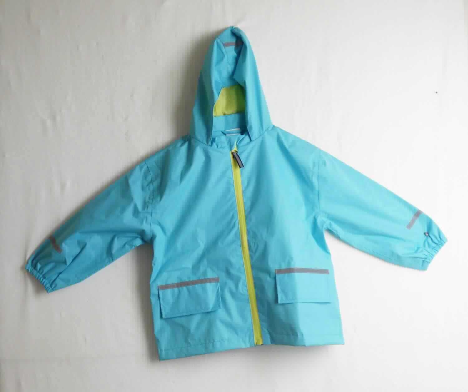 Anorak, sog. K- Matsch- u. Buddeljacke, Art. 288117, Größe 74/80, Foto siehe Anlage,
- veranschaulicht durch ein Warenmuster in Größe 98/104,
- aus ca. 0,1 mm dicken, einfarbigen Geweben aus laut Antrag 100 % Polyester (synthetische 
  Chemiefasern), die Gewebe sollen laut Antrag einseitig mit Kunststoff bestrichen sein, ein Bestreichen mit 
  Kunststoff ist jedoch mit bloßem Auge nicht wahrnehmbar (keine Meterware der Position 5903),
- durchgehend gefüttert,
- über den Schritt reichend,
- mit einem Stehkragen und einer Kapuze,
- vorn mit einer durchgehenden Öffnung mit einem bis an den Kragenrand reichenden Reißverschluss, 
  am Kragenrand mit einer kurzen Überlappung von rechts über links,
- mit langen Ärmeln, an den Ärmelenden elastisch verengt,
- mit zwei eingesetzten Taschen mit Patten unterhalb der Taille,
- mit mehreren aufgenähten, reflektierenden Streifen,
- am unteren Rand durch Umschlagen und Festnähen gesäumt,
- ist für Kleinkinder mit einer Körpergröße von bis zu 86 cm bestimmt.

"Kleidung für Kleinkinder, aus Geweben, aus synthetischen Chemiefasern"