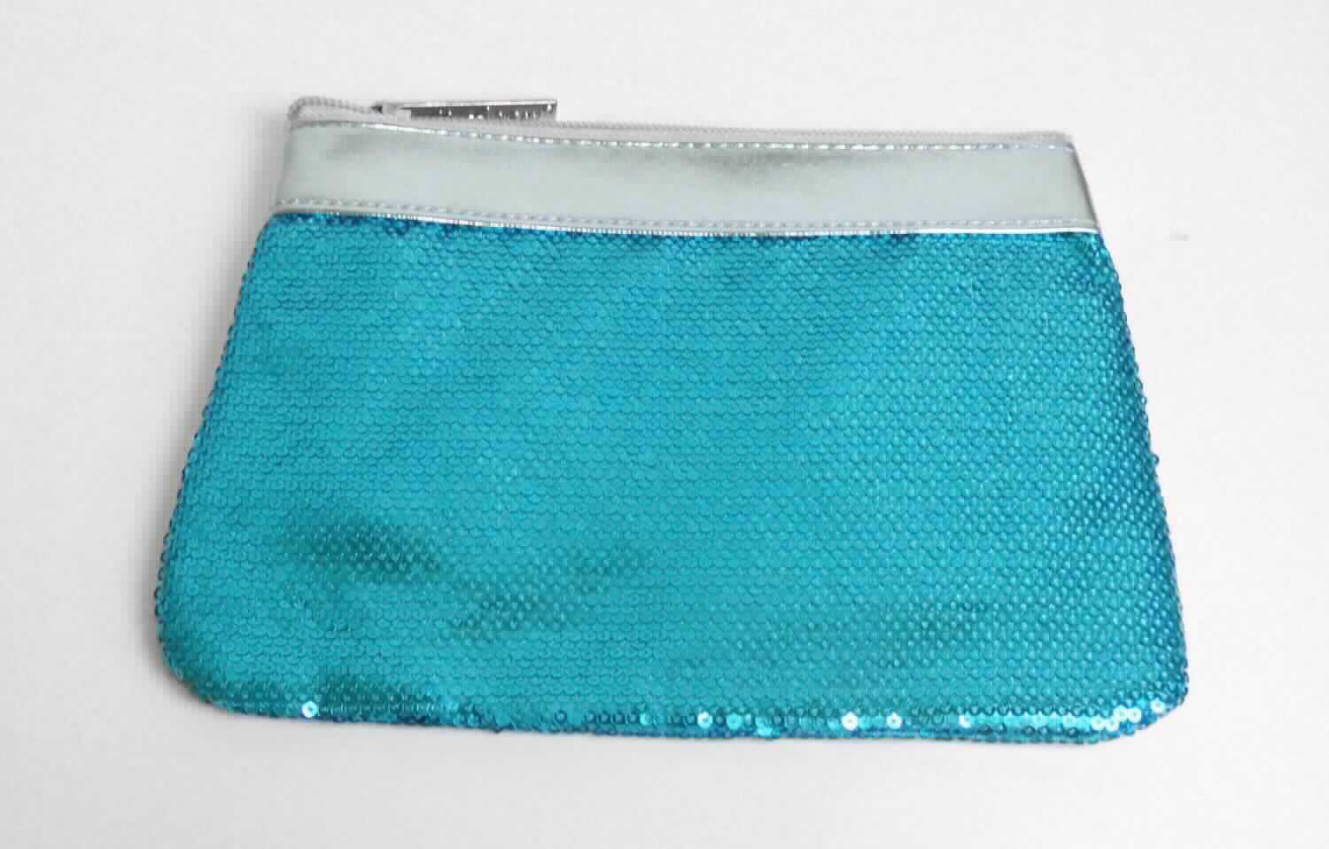 Ähnliches Behältnis, sog. flache Kosmetiktasche, Foto siehe Anlage,
- mit einer Außenseiten aus mit Pailletten bestickten Geweben aus Spinnstoffen der Position 5810 (Applikations-
  stickerei), wobei die Pailletten aus Kunststoff das Gewebe aus Spinnstoffen bedecken und den mit bloßem Auge
  wahrnehmbaren Stoff an der Oberfläche bilden; lediglich am oberen Rand des Behältnisses mit einer Außenseite
  aus silberfarbener Kunststofffolie,
- mit einem entlang des oberen Rands verlaufenden Reißverschluss,
- gefüttert; ohne weitere Innenausstattung,
- in den Abmessungen: ca. 22 cm (max. Breite) x 15 cm (Höhe).

"Ähnliches Behältnis, anderes als in den Unterpositionen 4202 1110 bis 4202 3900 genannte, mit einer anderen
 Außenseite als in den Unterpositionen 4202 9110 bis 4202 9298 genannte, kein handgearbeitetes Behältnis für
 Musikinstrumente"