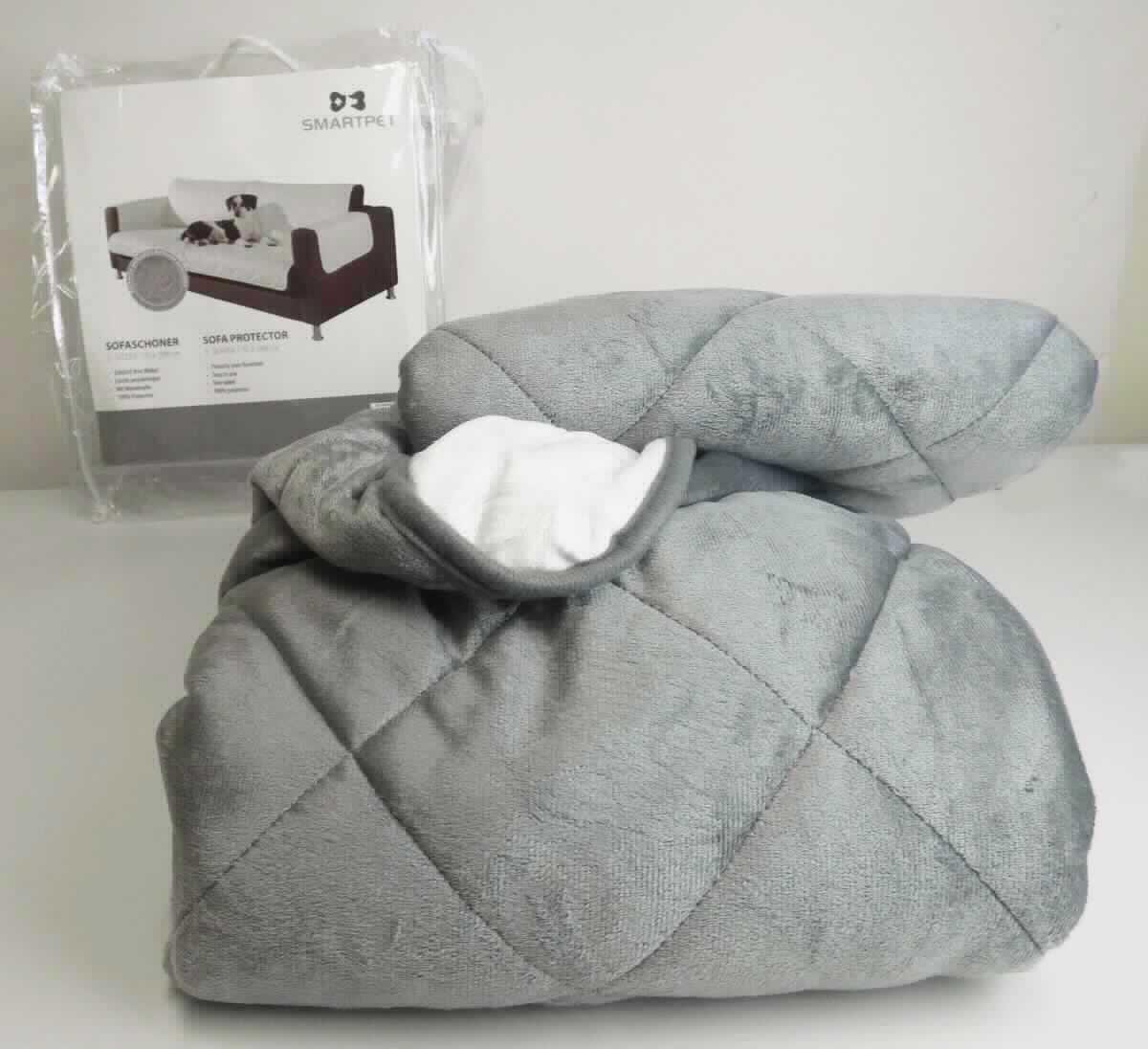 Sofaschoner, sog. Smartpet Sofaüberwurf, Fotos siehe Anlage,
- in einer einfachen Aufbewahrungstasche aus Kunststoff verpackt [übliche Verpackung i. S. d. AV 5 b)],
- kreuzförmig, als Wende-Sofaschoner gearbeitet; laut Antrag in den Abmessungen: 170 cm x 298 cm,
- aus dreilagigen, durch Steppen abgeteilten Flächenerzeugnissen (Meterwaren der Position 5811) mit zwei 
  äußeren Lagen aus verschiedenen einfarbigen (grau und weiß) Samtgewirken aus laut Antrag 100 % Polyester
  (synthetische Chemiefasern) und einer Zwischenlage aus Wattierungsstoff, 
- an den Rändern mit schmalen Streifen aus einfarbigen Gewirken eingefasst,
- durch Zusammennähen konfektioniert,
- dient laut Antrag dem Schutz des Sitzmöbels; wird als Zubehör für Sitzmöbel nicht vom Warenkreis der 
  Position 9401 erfasst und stellt sich damit als Ware zur Innenausstattung dar, 
- u. a. aufgrund des Verwendungszwecks und der Form keine Ware der Position 9404.

"Andere Ware zur Innenausstattung (Sofaschoner) aus Spinnstoffen, keine Ware der Position 9404, aus 
 Gewirken"