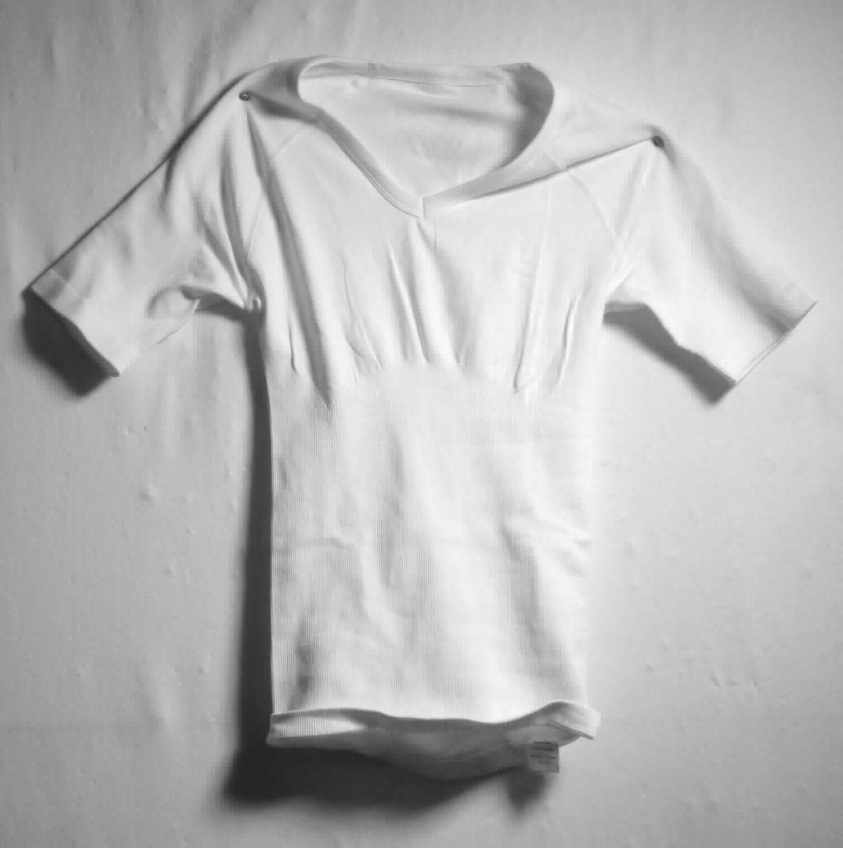 Formhemd, sog. Herren Kurzarm V-Neck, Größe M, Foto siehe Anlage,
- aus bis zu 1,2 mm dicken, einfarbigen, unterschiedlich strukturierten Gewirken aus laut Antrag 90 % Nylon
  und 10 % Elasthan (beides synthetische Chemiefasern),
- in der Art eines T-Shirts gearbeitet,
- über die Taille reichend (Rückenlänge: ca. 60 cm),
- mit einem V-Ausschnitt mit einer Randeinfassung,
- ohne Öffnung und ohne Verschluss,
- mit kurzen, enganliegenden Ärmeln,
- am unteren Rand und an den Ärmelenden durch Umschlagen und Festnähen gesäumt, 
- nach Ausstattung und Material dazu bestimmt, gewisse Teile des Körpers zu stützen, zu formen und 
  zu korrigieren,
- u. a. aufgrund der verarbeiteten Flächenerzeugnisse keine Ware der Position 6207.

"Den Korsetten ähnliche Ware, aus Gewirken, andere als in den Unterpositionen 6212 10 bis 6212 30 genannte"