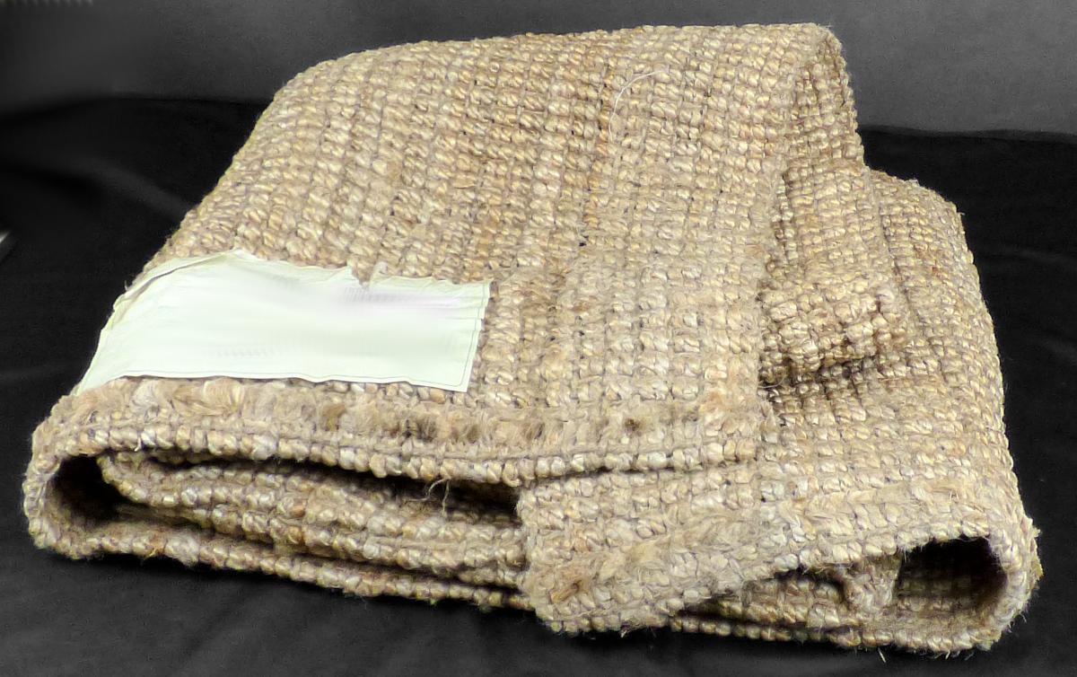 Teppich, sog. Juteteppich, Foto siehe Anlage,
- quadratisch, mit den Abmessungen von laut Antrag ca. 150 cm x 150 cm,
- aus einem buntgewebten Gewebe aus laut Antrag Jute,
- an zwei Seiten durch Umschlagen und Festnähen gesäumt (somit konfektioniert),
- kein Kelim, Sumak, Karamanie oder denen ähnlicher handgewebter Teppich, somit keine Ware der
  Unterposition (HS) 5702 10,
- ohne Flor; weder getuftet noch beflockt,
- erfüllt die Bedingungen zur Einreihung als Teppich.

"Teppich, aus Spinnstoffen, gewebt, weder getuftet noch beflockt, konfektioniert, kein Kelim,
 Sumak, Karamanie und ähnlicher handgewebter Teppich, aus Jute, ohne Flor"
