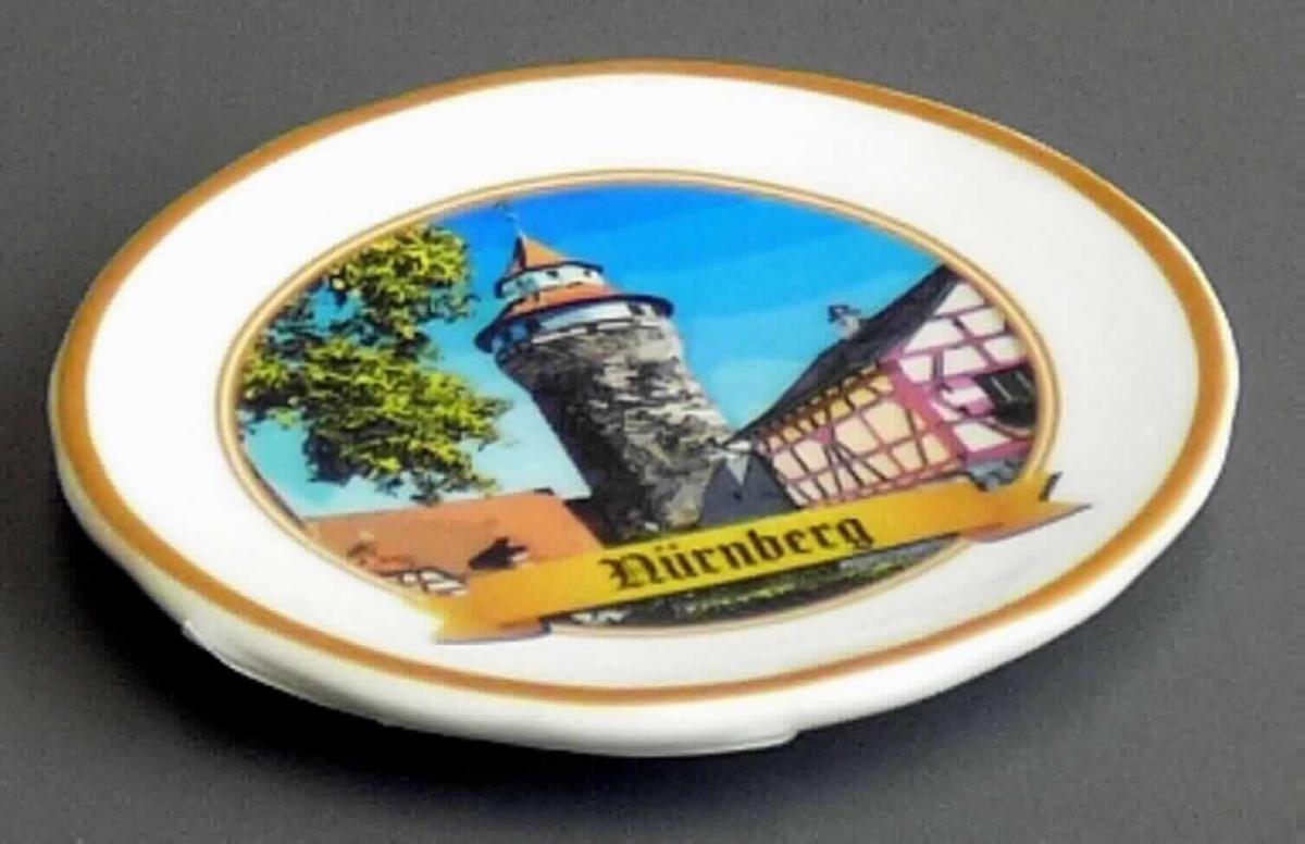 Keramischer Ziergegenstand, sog. Magnet Nürnberg, SOUVENIR, Art. 732076, Foto siehe Anlage, 
- aus verschiedenen Bestandteilen zusammengesetzte Ware, bestehend aus: 
- einem keramischen Ziergegenstand in Form eines kleinen Ziertellers: 
- - glasierter, weißer, runder Teller,
- - auf der Vorderseite mit einem Stadtmotiv und einem Schriftzug "Nürnberg" versehen, 
- - in den Abmessungen: ca. 5,5 cm (Durchmesser) x 1 cm (Höhe), 
- - keramisches Erzeugnis, nach der Formgebung gebrannt, tonmineralhaltiges Material enthaltend, 
- - lt. Antrag aus Porzellan, 
- - ohne Hinweise auf Handarbeit, 
- einem runden Dauermagneten:
- - Durchmesser: ca. 1,2 cm,
- - an der Rückseite des Tellers festgeklebt, 
- - dient zur Befestigung des Tellers auf einer metallischen Unterlage und darüber hinaus ggf. von z. B. 
    Notizzettel auf Metallunterlagen,
- der keramische Ziergegenstand bestimmt nach der Bedeutung in Bezug auf die Verwendung und seinem Wert 
  den wesentlichen Charakter der zusammengesetzten Ware. 

"Keramischer Ziergegenstand, aus Porzellan, nicht handgearbeitet."