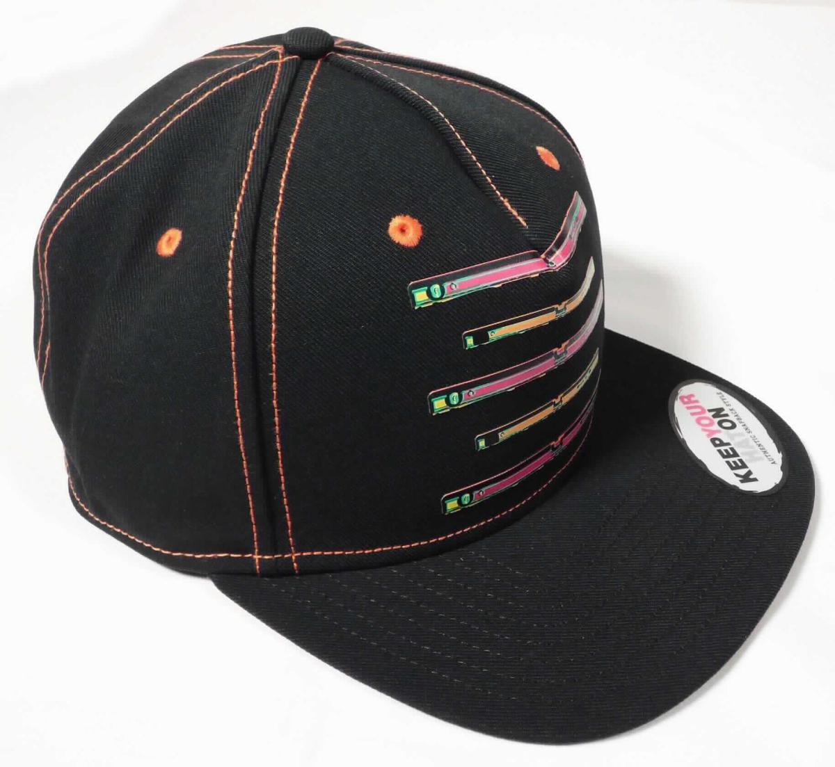 Kopfbedeckung (Mütze), sog. Cap Pop Art e.s. Vintage (A3-Art. 7810700), Foto siehe Anlage,
- durch Zusammennähen von Stücken aus Geweben aus Spinnstoffen (laut Antrag aus 100 % Polyester)
  hergestellt,
- schwarz; mit orangefarbenen Ziernähten; vorn mit fünf Wasserwaagen als Motiv bedruckt,
- mit einem Knopf an der Stelle, an der die Nähte zusammenlaufen, 
- mit Schirm,
- im hinteren Teil mit einem Riegel aus Kunststoff zum Einstellen der Weite,
- mit sechs kleinen Luftlöchern versehen,
- innen mit einem Schweißband ausgestattet.

"Kopfbedeckung, aus mehreren Stücken von Spinnstofferzeugnissen hergestellt, Mütze mit Schirm"
