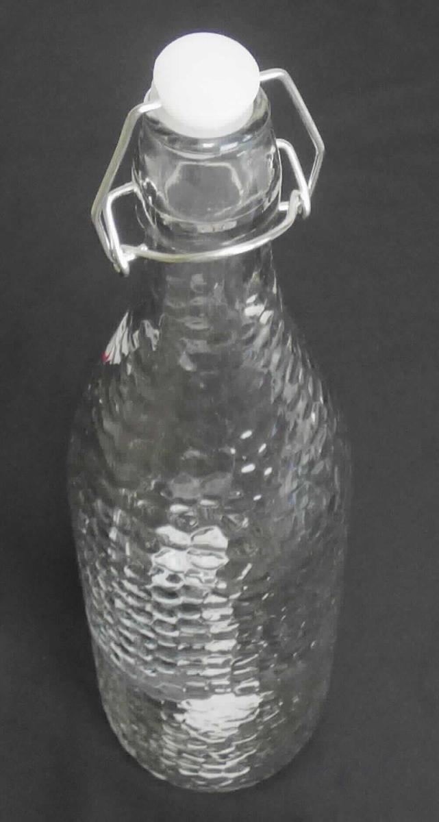 Flasche aus Glas, sog. Glasflasche mit Bügelverschluss, Artikel 19759, Foto siehe Anlage,
- aus nicht gefärbtem Glas (nicht aus Glasröhren hergestellt); mit wabenartiger Struktur,
- mit einem Bügelverschluss aus unedlem Metall und einem Stopfen aus Kunststoff mit einem 
  Dichtungsring,
- mit einem Fassungsvermögen (Nenninhalt) von 1000 ml,
- in den Abmessungen: ca. 8,5 cm (Durchmesser) x 30 cm (Höhe),
- zur Aufnahme von Nahrungsmitteln oder Getränken.

"Flasche aus Glas, zu Transport- oder Verpackungszwecken, nicht aus Glasröhren hergestellt, 
 aus nicht gefärbtem Glas, mit einem Nenninhalt von 1 l, für Nahrungsmittel und Getränke"