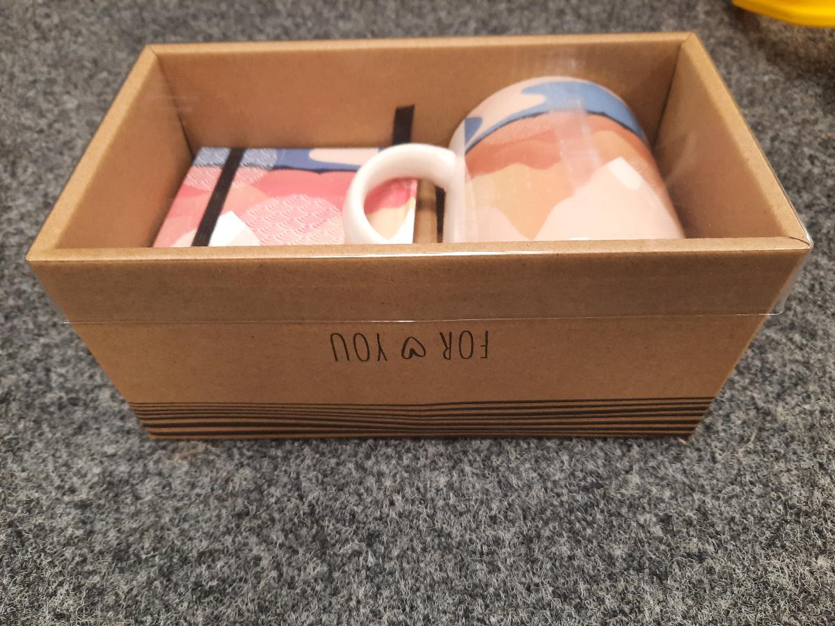 Zweiteilige Zusammenstellung, bestehend aus Geschirr (Tasse) und einem Notizbuch, sog.
Geschenkset Tasse und Notizbuch, Foto siehe Anlage,
- in einem Pappkarton für den Einzelverkauf aufgemacht,
- die Waren dienen weder der Befriedigung eines speziellen Bedarfs noch der Ausübung einer
  bestimmten Tätigkeit und stellen somit keine Warenzusammenstellung im Sinne der AV 3 b) dar,
- Notizbuch:
- - klebegebunden,
- - in den Abmessungen: ca. 9 cm x 9 cm x 1,5,
- - mit 100 Blatt liniertem Papier in einem festen Umschlag aus bedruckter Pappe (auf den
     Außenseiten mit einem Muster farbig bedruckt),
- - mit einem elastischen Band aus Spinnstoffen zum Verschließen ausgestattet,
- - soll zum handschriftlichen Eintragen von persönlichen Notizen und Skizzen dienen.

"Notizbuch ohne Kalendarium, aus Papier oder Pappe"