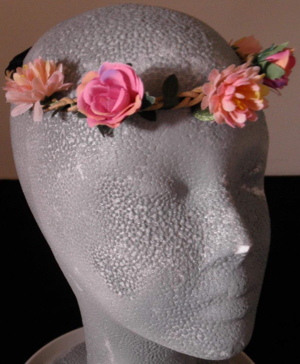 Kopfband mit künstlichen Blumen, sog. Haarkranz Blumen, Art. 8663284, 8718390, Foto siehe Anlage,
- stellt sich als zusammengesetzte Ware dar,
- Kopfband:
-- mit einem Umfang von ca. 50 cm,
-- vorn aus einem ca. 34 cm langen, geflochtenen "Band" aus drei ca. 1,6 mm schmalen Rundgeflechten 
   und einem max. ca. 12 mm breiten Streifen aus Geweben, der so geschnitten ist, dass in regelmäßigen
   Abständen auf beiden Längsseiten "Blätter" abstehen,
-- an den Enden mit einem ca. 16 cm langen und ca. 6 mm breiten, elastischen Flachgeflecht der Po-
   sition 5808 ringförmig zusammengefügt (somit konfektioniert),
-- alle Geflechte und Gewebe aus Spinnstoffen,
-- ohne Hinweise auf Handarbeit,
-- wird zum Zurückhalten des Haares getragen,
-- individuelles (selbstständiges) Einzelstück, das eine Ergänzung von Kleidung darstellt,
-- aufgrund der verwendeten Flächenerzeugnisse keine Ware der Position 6117,
- künstliche Blumen:
-- fünf in regelmäßigen Abständen auf den vorderen Teil des Kopfbandes aufgeklebte, künstliche
   Blumen (max. Durchmesser ca. 3,5 cm),
-- mit Blütenblättern aus Geweben aus Spinnstoffen und einem "Blütenstempel" aus Kunststoff,
-- durch Zusammenkleben bzw. Zusammenstecken der einzelnen Elemente in Blumenbindetechnik 
   hergestellt,
- in Anbetracht des textilen Charakters wird die Ware nicht vom Warenkreis der Position 9615 erfasst,
- insbesondere im Hinblick auf die Verwendung verleiht das Kopfband der Ware ihren wesentlichen 
  Charakter (somit keine Ware der Position 6702).

"Anderes konfektioniertes Bekleidungszubehör (Kopfband), aus Spinnstoffen, nicht aus Gewirken
 oder Gestricken, nicht handgearbeitet"