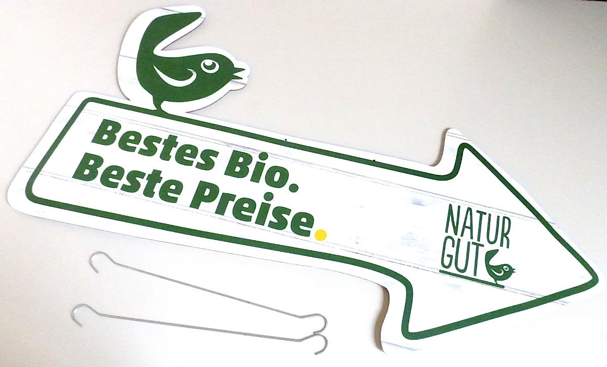 Es handelt sich um einen pfeilförmigen Zuschnitt aus Pappe mit den maximalen Abmessungen von etwa 77 x 38 cm, der beidseitig mit einem Logo und einem Werbeslogan farbig bedruckt ist. Der obere Rand ist mit einem ausgearbeiteten Vogel versehen und weist zwei Lochungen auf, durch die jeweils ein Haken aus unedlem Metall gesteckt wird. Das Erzeugnis dient zu Werbezwecken und wird in Geschäften an der Decke befestigt.
Der bedruckte Pappzuschnitt ist mit zwei Haken gemeinsam für den Einzelverkauf aufgemacht.

Im Hinblick auf die Bedeutung in Bezug auf die Verwendung verleiht der Werbedruck der Warenzusammenstellung den wesentlichen Charakter.  

Abbildung siehe Anlage. 

Derartige Erzeugnisse gehören als "andere Drucke, Werbedrucke, andere als Verkaufskataloge" zur Codenummer 4911 1090 00 0 des Zolltarifs.
