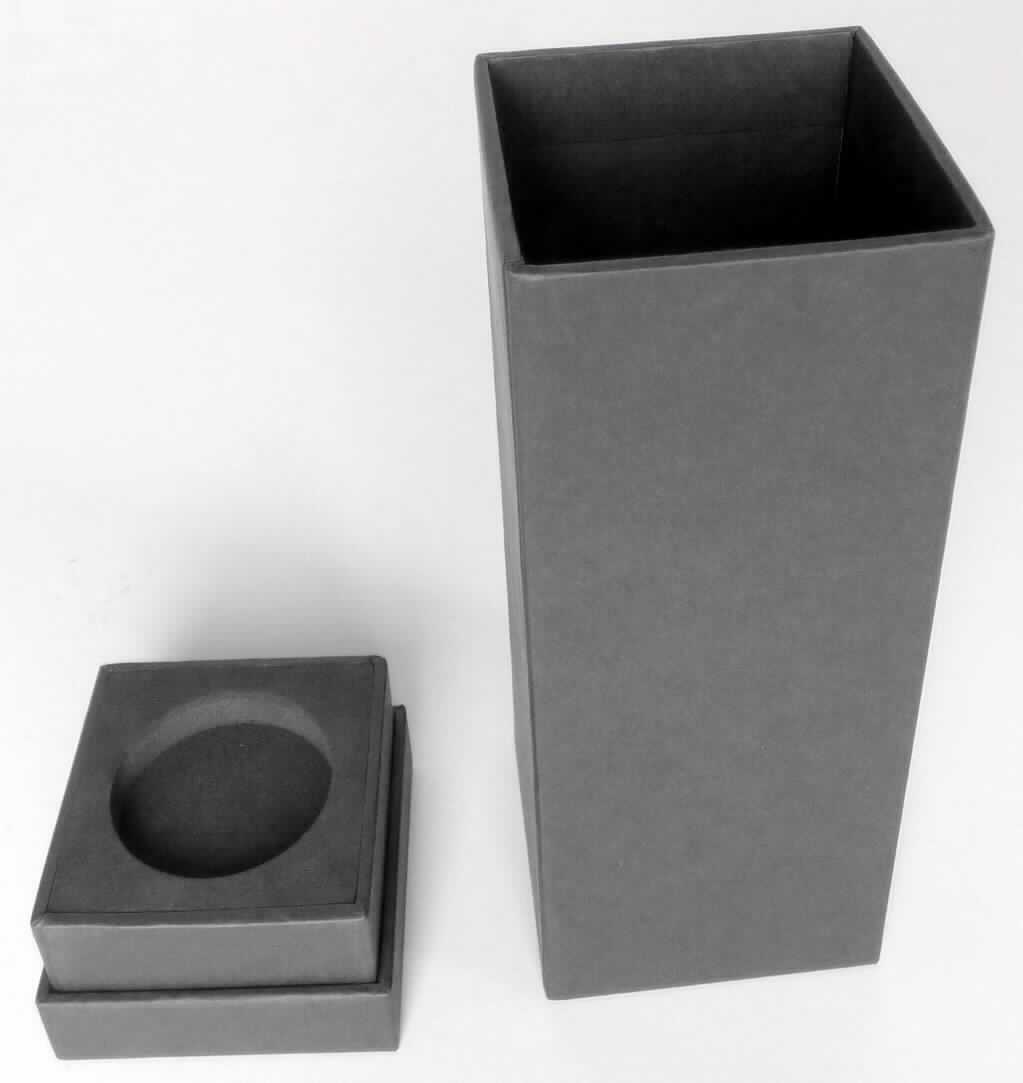 Schachtel für Flakon, sog. schwarze Stülpdeckelschachtel, Foto siehe Anlage,
- mit einer Außenseite aus schwarzem Papier auf einem formstabilen Korpus aus Pappe,
- in Form einer quaderförmigen Stülpschachtel mit einem Podest und einem abnehmbarem Deckel,
- mit einem eingeklebten Schaumstoffeinsatz im Podest und im Deckel,
- - jeweils mit einer kreisrunden Aussparung (passgenau für einen bestimmten Flakon),
- in den Abmessungen: ca. 20 cm (Höhe) x 6,5 cm (Seitenlänge).

"Schachtel für Flakon, mit einer Außenseite aus Papier"