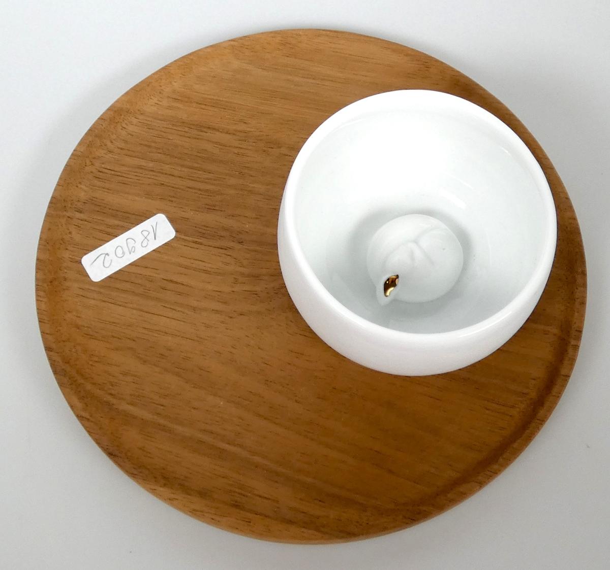Geschirr aus Porzellan, Foto siehe Anlage,
- in Form einer zusammengesetzten Ware, bestehend aus einem Schälchen aus Porzellan und
  einem Serviertablett aus Holz,
- Schälchen (Geschirr) aus Porzellan:
- - in Form eines weißen, leicht bauchigen, innen glasierten Schälchens; innen am Boden mit
     einem angearbeiteten, stilisierten, schlafenden Eichhörnchen versehen,
- - in den Abmessungen: ca. 8 cm (Durchmesser) x 4﻿,﻿5 cm (Höhe),
- - keramisches Erzeugnis; nach der Formgebung gebrannt; tonmineralhaltiges Material enthaltend,
- - laut Antrag aus Porzellan,
- Serviertablett (Holzware zur Verwendung bei Tisch):
- - laut Antrag aus Akazienholz,
- - an der Oberseite mit einer kreisrunden Vertiefung, die passgenau zum Einstellen des Schälchens
     gearbeitet ist,
- - in den Abmessungen: ca. 17 cm (Durchmesser) x 1﻿,﻿3 cm (Höhe),
- das Schälchen aus Porzellan bestimmt nach dem Wert und aufgrund seiner Bedeutung in Bezug
  auf die Verwendung den wesentlichen Charakter der zusammengesetzten Ware.

"Geschirr (Schälchen), aus Porzellan"