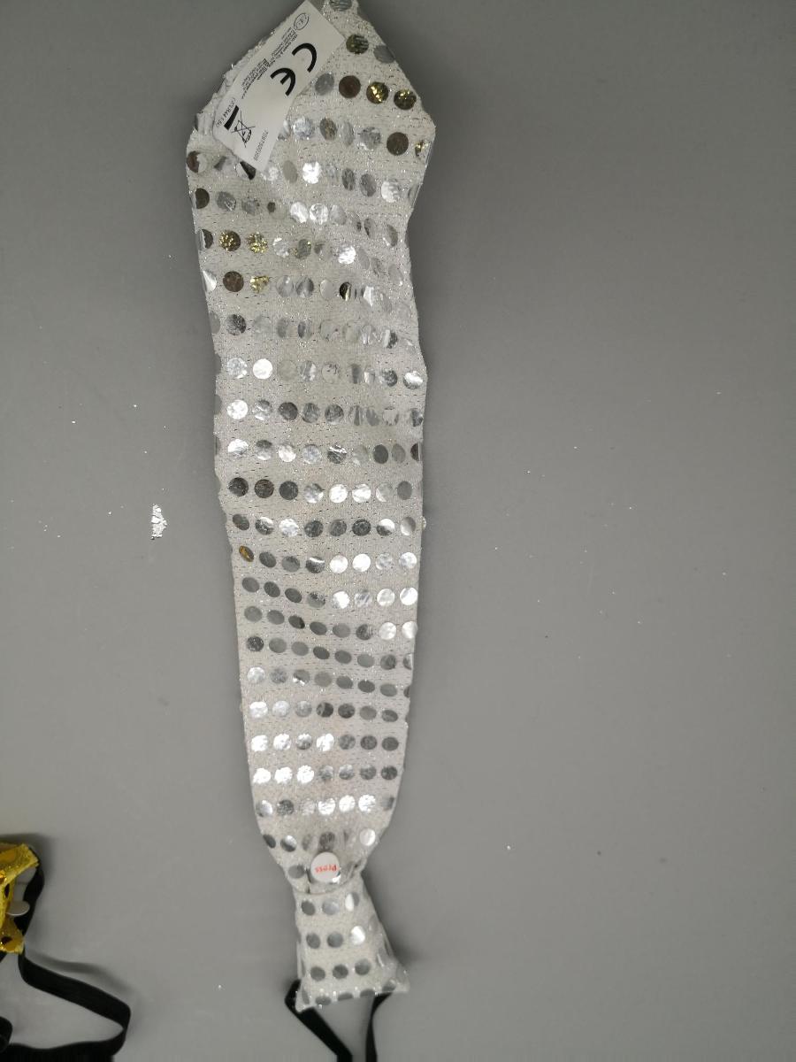 Krawatte, Foto siehe Anlage,
- mittels Polystring an einer Gebrauchsanleitung befestigt,
- laut Antrag in drei unterschiedlichen Farbausführungen,
- in den max. Abmessungen von ca. 33 cm x 8 cm,
- aus einem zweilagigen Textillaminat aus laut Antrag 100 % Polyester (synthetische Chemie-
  fasern): mit einer im Hinblick auf das äußere Erscheinungsbild charakterbestimmenden 
  Außenlage (Schauseite) aus einfarbigen Gewirken (weder elastisch noch kautschutiert), die 
  mit aufgeklebten Pailletten verziert sind, und einer Innenlage aus Vliesstoffen,
- in gebundener Form, mit einem angenähten, elastischen Band zur Befestigung am Hals ver-
  sehen,
- mit einer eingearbeiteten Lichterkette mit mehreren LED-Brennstellen, einem Batteriefach 
  (mit Batterien) sowie am "Knoten" mit einem An-/Aus-/Modusschalter ausgestattet,
- durch Zusammenfügen konfektioniert,
- individuelles (selbstständiges) Einzelstück, das eine Ergänzung von Kleidung darstellt,
- mit eigenem Gebrauchswert, somit keine Ware der Position 9505.

"Anderes konfektioniertes Bekleidungszubehör (Krawatte), aus (weder elastischen noch 
 kautschutierten) Gewirken"