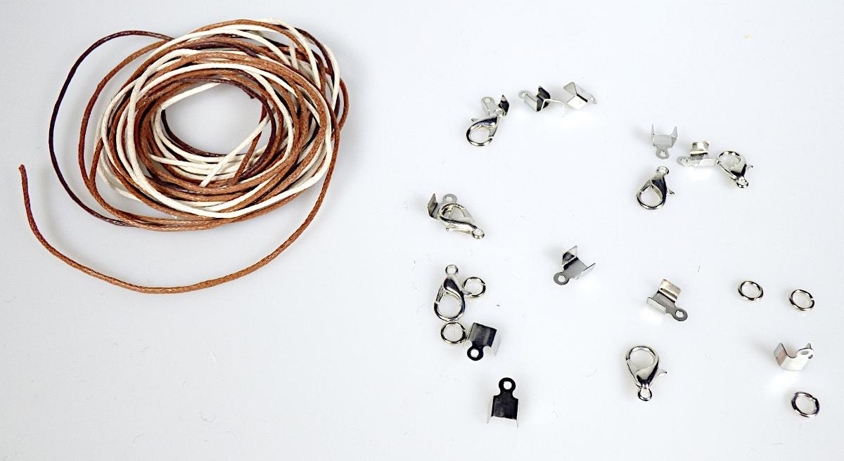 Es handelt sich um aus unedlem Metall gefertigte, noch nicht zusammengesetzte Verschlusselemente für Armbänder, bestehend aus
- einem kleinen Haken mit ferderndem Verschlussmechanismus, einseitig zu einer Öse ausgearbeitet,
- einer nicht gänzlich geschlossenen Öse aus Draht,
- zwei einseitig zu Ösen ausgearbeiteten Klemmverschlussteilen.
Die Erzeugnisse sind gemeinsam als Bastelset, (sog Schmuckband-Set, Artikelnr. 273045) mit fünf noch nicht zusammengesetzten Armbändern aus textilem Bastelband, Ösen, Klemmverschlussteilen und Karabinerhaken (jeweils nicht Gegenstand dieser vZTA) in einem klarsichtigen Kunststoffbeutel verpackt und auf einer bedruckten Papunterlage befestigt.

Die vorliegenden Verschlusselemente stellen sich als überzählige Ersatzteile dar, für die in Anwendung der Allgemeine Vorschrift 2 a) die Einreihung getrennt vorzunehmen ist.

Sie sind somit als "Verschlüsse aus unedlen Metallen, für Schmuck" in den TARIC-Code 8308 9000 90 einzureihen.

Abbildung siehe Anlage.