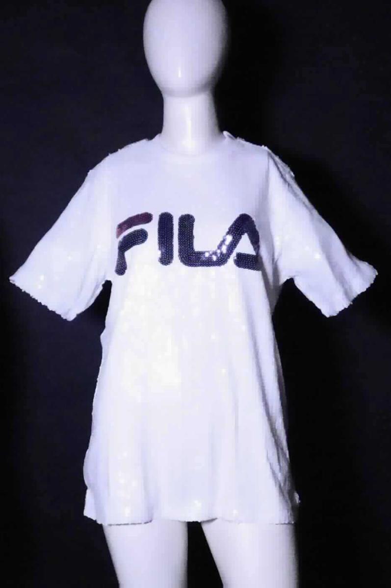 Bluse, sog. FILA Nero KYO Sequin T-Shirt, Größe S, Foto siehe Anlage,
- doppellagig gearbeitet; beide Lagen durch Zusammennähen miteinander fest verbunden; mit einer Außenlage aus
  Applikationsstickereien (Pailletten) der Position 5810 mit einem Stickgrund aus ca. 0,1 mm dicken, einfarbigen,
  netzartig durchbrochenen Gewirken und einer Innenlage aus ca. 0,4 mm dicken, einfarbigen Gewirken; beide
  Flächenerzeugnisse aus laut Antrag 100 % Polyester (synthetische Chemiefasern); stellt sich aufgrund der 
  Gesamtdicke von 0,5 mm noch als leichtes Kleidungsstück dar,
- über den Schritt reichend (Rückenlänge: ca. 71 cm),
- mit einem runden Halsausschnitt mit gewirkter Randeinfassung,
- ohne Öffnung und ohne Verschluss,
- ohne Hinweise auf den Trägerkreis (unisex),
- mit kurzen Ärmeln,
- am unteren Rand durch Umschlagen und Festnähen gesäumt,
- insbesondere im Hinblick auf das Erscheinungsbild bestimmt die äußere Lage aus Stickereien der Position 5810
  den Charakter der Ware (damit keine Kleidung des Kapitels 61).

"Bluse, aus Stickereien, für Frauen, aus Chemiefasern"