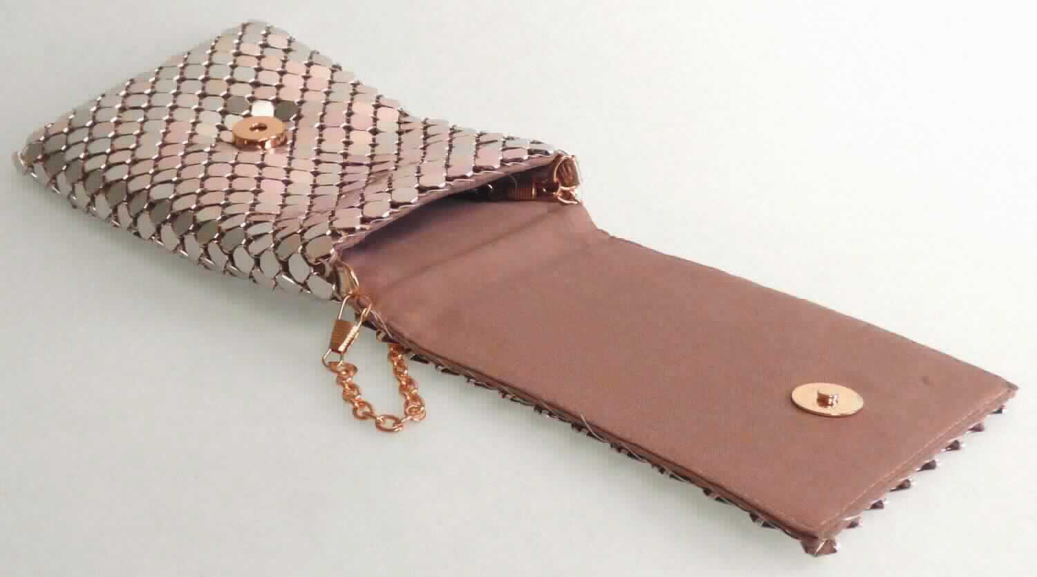 Handtasche, sog. Tasche (Metall), Foto siehe Anlage, 
- mit einem Korpus aus Spinnstoffen,
- mit einer Außenseite aus miteinander verketteten, silberfarbenen Metallplättchen,
- mit einem Schultertrageriemen in Form einer Gliederkette aus unedlem Metall, 
- mit einer Überschlagklappe mit Magnetknopfverschluss,
- gepolstert gefüttert, ohne Inneneinteilung, 
- mit den Abmessungen von ca. 12 cm (Länge) x 19 cm (Höhe) x 2 cm (Tiefe), 
- aufgrund der Form, der Größe und des Gesamteindrucks in erster Linie dazu geeignet, 
  kleinere persönliche Gegenstände aufzunehmen.

"Handtasche, aus Spinnstoffen, mit einer anderen Außenseite als die in den Unterpositionen 4202 2100 bis 
  4202 2290 genannten"