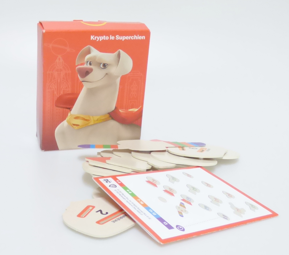 Bei dem vorliegenden und als "McDonald's - DC League of Super Pets Paper - 2022 - Krypto the Superdog A" bezeichneten Erzeugnis handelt es sich um einen Bausatz,
- einen sitzenden Hund mit rotem Umhang darstellend,
- aus Pappe gefertigt,
- bestehend aus 14 bedruckten Einzelteilen,
- - mit einem Gesicht mit zwei seitlich abstehenden Laschen, die
    derart bedruckt sind, dass sie die Reihenfolge der anderen Bauteile
    vorgeben,
- - die Laschen werden hinter das Gesicht geklappt,
- - die anderen Bauteile sind mit zwei farblich markierten Aussparungen
    versehen sowie entsprechend nummeriert und müssen in der richtigen
    Reihenfolge auf die Laschen gesteckt werden,
- mit einem runden Aufkleber, der auf den Rücken der zusammengesetzten
  Figur geklebt wird um diese zusammenzuhalten,
- die Einzelteile sind alleine nicht zum Spielen geeignet und sinnvoll
  aufeinander abgestimmt,
- dient der spielerischen Unterhaltung von Kindern,
- gemeinsam mit einer Bauanleitung in einem Pappkarton verpackt.

Derartige Erzeugnisse sind zolltarifrechtlich als "anderes als in den Unterpositionen (KN) 9503 0010 bis 9503 0030 erfasstes Spielzeug, Bausatz, nicht aus Kunststoff oder handgearbeitet aus Holz" einzureihen.
