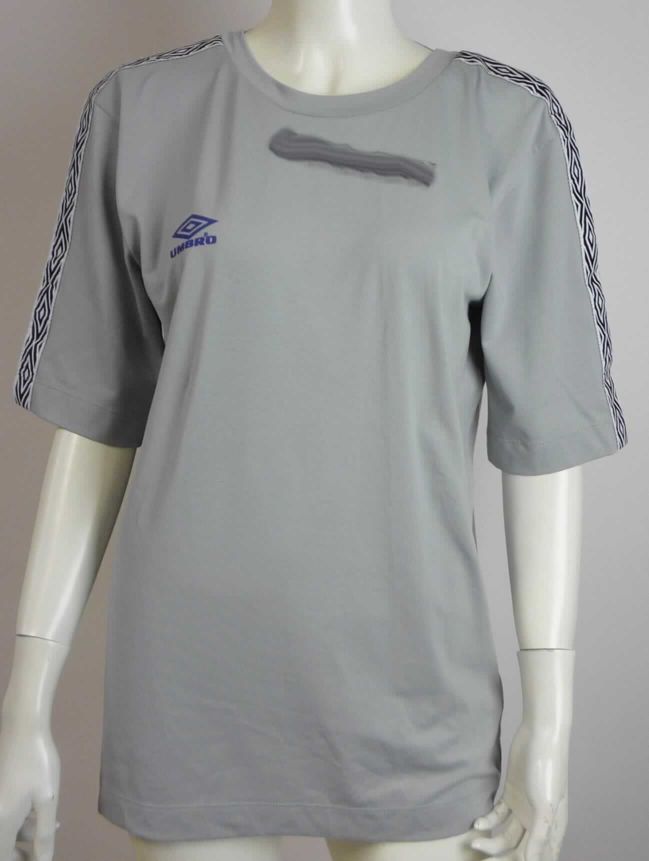 Modisches Unterhemd, sog. Umbro T-Shirt, Art. UZ2WW1817, Größe S, Foto siehe Anlage,
- aus ca. 0,6 mm dicken (leichten), einfarbigen Gewirken aus laut Antrag 100 % Baumwolle,
- bis über den Schritt reichend (Rückenlänge: ca. 70 cm),
- vorn mit einem runden Ausschnitt, im Rückenteil mit einem bis zur Rückenmitte reichenden Aussparung (somit 
  kein T-Shirt), die Halslinie wird jedoch durch ein in Höhe des Nackens am linken und rechten Rand des 
  Ausschnitts vernähtes, schmales Band aus Gewirken gebildet, welches das Herunterrutschen des 
  Kleidungsstücks von der Schulter verhindern soll, somit kein sehr tiefer Halsausschnitt,
- ohne Öffnung und ohne Verschluss,
- mit kurzen Ärmeln,
- im Bereich der Schultern und Ärmel mit aufgenähten Zuschnitten aus buntgewebten Geweben,
- modisch gestaltet; wird unmittelbar auf der Haut getragen,
- an den Ärmelenden und am unteren Rand durch Umschlagen und Festnähen gesäumt.

"Unterhemd, aus Gewirken, aus Baumwolle"