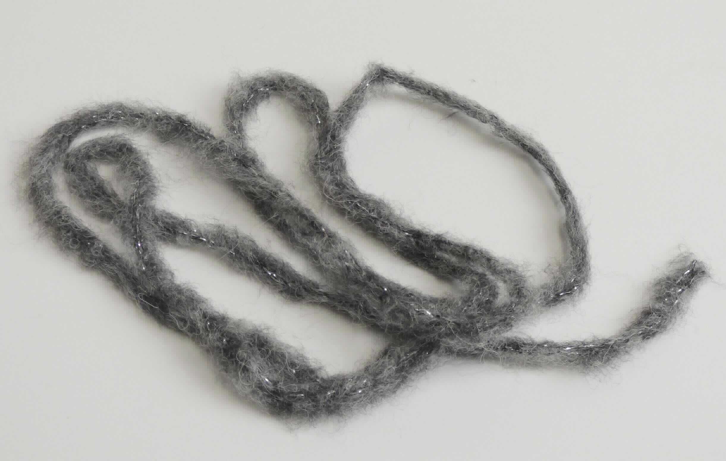 Gewirke, sog. Handstrickgarn Hollywood, Art. 3798, Foto siehe Anlage,
- als Meterware im Knäuel, laut Antrag mit einer Länge von 80 m,
- laut Untersuchungsergebnis:
-- schlauchförmiges Gewirke mit einer Breite von ca. 5 mm (damit kein Maschengarn der Position 5606),
-- aus überwiegend synthetischen Chemiefasern (laut Antrag Polyacryl und Polyamid) sowie Wolle und metallisierten 
   Streifen aus synthetischer Spinnmasse mit einer Breite von weniger als 1 mm (laut Antrag Polyester), 
-- die Antragsangaben von 56 GHT synthetischen Chemiefasern, 36 GHT Wolle und 8 GHT metallisierten Streifen 
   können als zutreffend angesehen werden,
-- keine Elastomergarne oder Kautschukfäden enthaltend,
-- keine Raschelspitze,
- ohne Flor- oder Schlingenoberfläche.

"Gewirke, mit einer Breite von weniger als 30 cm, anderes als solche der Positionen 6001 und 6002, aus 
 synthetischen Chemiefasern, keine Raschelspitze"