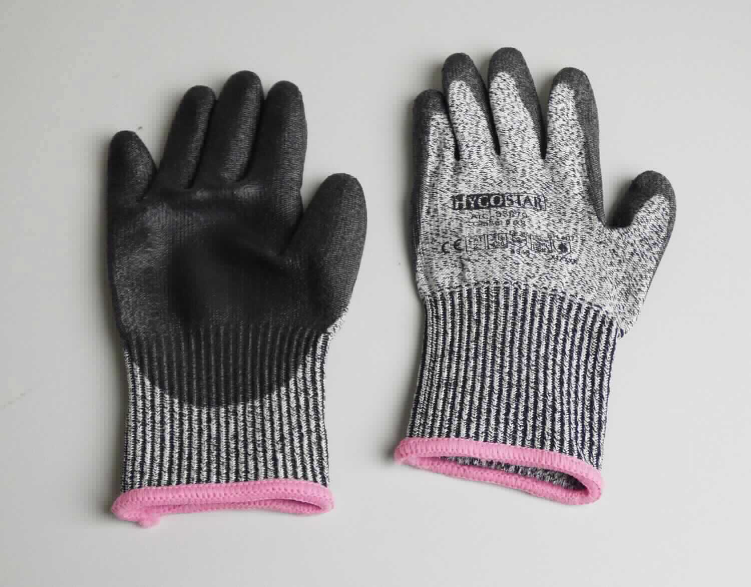 Fingerhandschuhe, sog. Schnittschutz-Handschuhe, in Erwachsenengröße, Foto siehe Anlage,
- als Fünffingerhandschuhe gearbeitet,
- aus buntgewirkten Gewirken (melierte Garne) aus laut Antrag Polyester (synthetische Chemiefasern),
- abgepasst gewirkt,
- nachträglich mit Ausnahme des größten Teils der Stulpe, des Handrückens und Teilen der Finger- und Daumen-
  außenseiten einseitig (Außenseite) im Tauchverfahren mit Kunststoff (lt. Antrag: Polyurethan; keine Zellstruktur 
  erkennbar) überzogen,
- im Bereich des Handrückens mit einem Aufdruck versehen,
- mit einer elastischen Stulpe,
- am unteren Rand durch eine kontrastfarbene Überwendlichnaht gesäumt.

"Fingerhandschuhe, aus Gewirken, mit Kunststoff überzogen"
