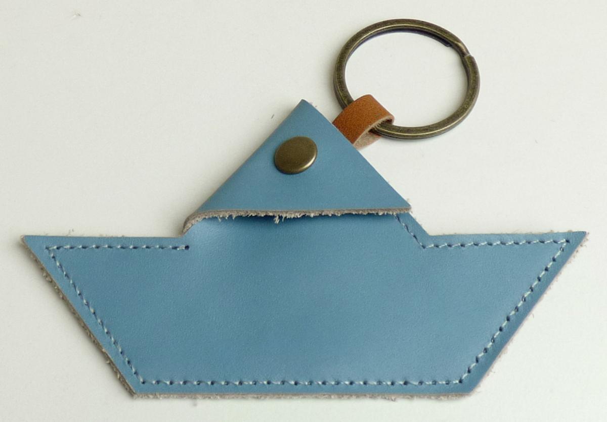 Behältnis ähnlich einer Geldbörse, sog. kleine Geldbörse aus Leder mit Schlüsselring, Foto siehe Anlage,
in Form einer zusammengesetzten Ware, bestehend aus:
- einem Geldbörsen ähnlichen Behältnis,
- - mit einer Außenseite aus Leder,
- - mit einem Druckknopfverschluss,
- - mit einem Fach für Münzen (Kleingeld), ungefüttert,
- - geschlossen in Form eines Schiffes, geöffnet in Form eines Haifisches,
- - mit den Abmessungen (geschlossen): ca. 12,2 cm (Breite) x 7,1 cm (H) x 0,4 cm (Tiefe),
- - ohne Hinweise auf Handarbeit,
- einem Schlüsselring,
- - aus unedlem Metall,
- - mit einer Schlaufe aus Leder an dem Geldbörsen ähnlichen Behältnis befestigt,
- das Geldbörsen ähnliche Behältnis bestimmt u. a. aufgrund seiner Bedeutung in Bezug auf die
  Verwendung den wesentlichen Charakter der zusammengesetzten Ware.

"Geldbörsen ähnliches Behältnis, Taschen- oder Handtaschenartikel, mit Außenseite aus Leder,
 nicht handgearbeitet"
