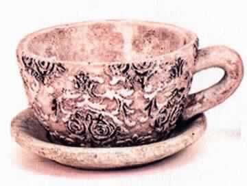 Angaben:
Pflanztasse mit Rosenmotiv aus Zement; Durchmesser: 16 cm, Höhe: 8,5 cm; mit Loch in der Mitte, zum Abfließen des Gießwassers. Unterteller Durchmesser 18 cm; zur Dekoration von Wohnräumen oder Terrassen.

Warenbeschaffenheit:
Graue Tasse mit Loch im Boden, mit Ornamenten verziert sowie graue Untertasse. Der Artikel besteht aus einer harten, grauen, heterogenen, mineralischen Masse mit Einschlüssen.

Befund:
Ware aus Zement, Beton oder Kunststein, auch bewehrt