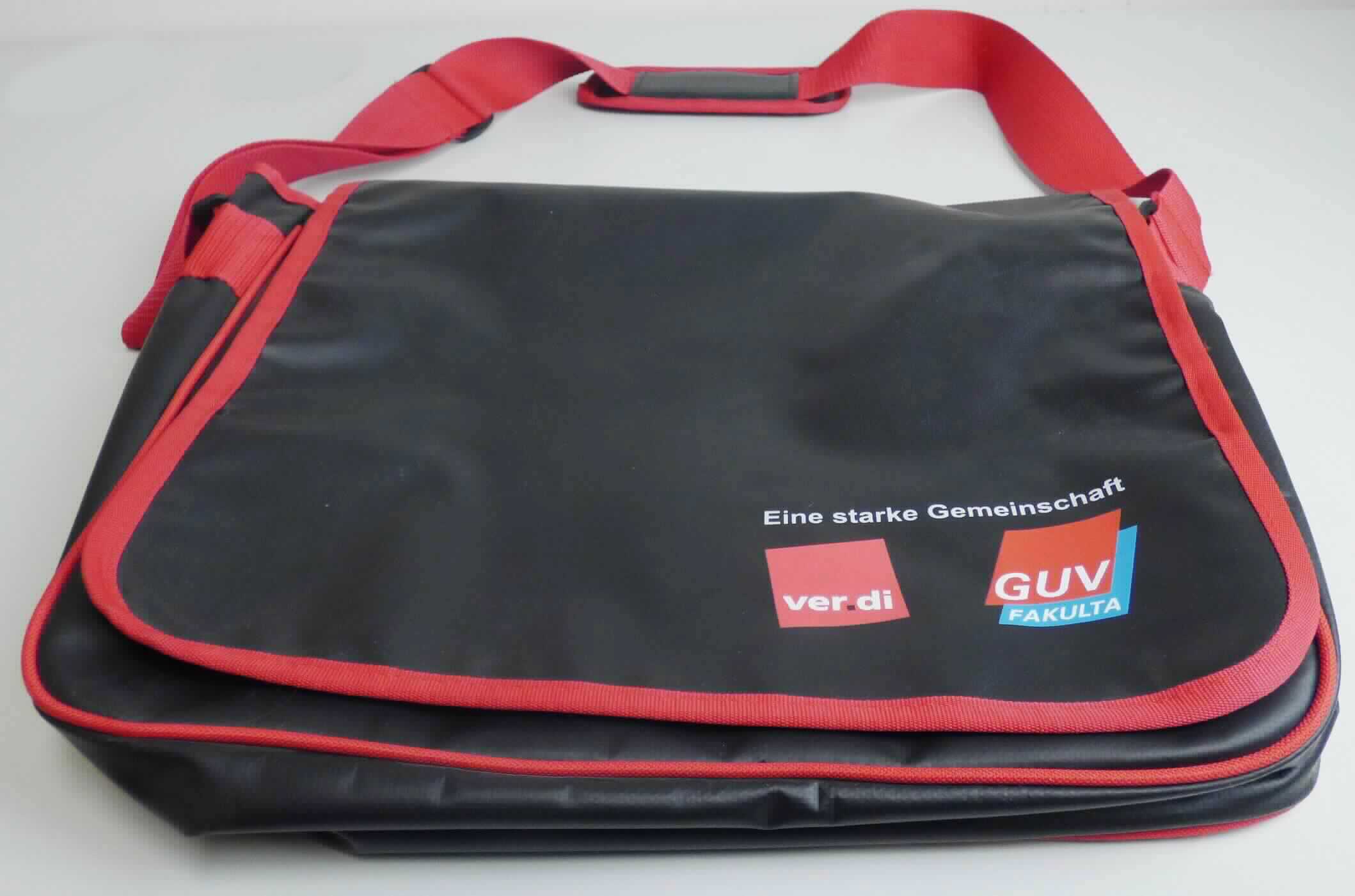 Aktentaschenähnliches Behältnis, sog. Überschlagtasche aus Tarpaulinmaterial, Foto siehe Anlage, 
- mit einer Außenseite aus schwarzen Kunststofffolien, 
- mit einem verstellbaren Schultertragegurt versehen, 
- mit einer über die gesamte Vorderfront reichenden Überschlagklappe mit zwei Klettverschlüssen;
  mit einem Gewerkschaftslogo bedruckt,
- unter der Überschlagklappe mit einem eingesetzten Reißverschlussfach; darauf aufgesetzt mit einem Handyfach
  mit Überschlagklappe, drei offenen Einsteckfächern, einem Reißverschlussfach und drei Einsteckfächern
  zur Aufnahme von Stiften,
- mit einem Hauptfach, 
- - innen mit einem gepolsterten Notebookfach mit Klettverschlusslasche ausgestattet; ansonsten ohne weitere
    Einteilung oder Ausstattung,
- - gefüttert, 
- mit den Abmessungen von ca. 37 cm (Breite) x 34 cm (Höhe) x 10 cm (Tiefe).

"Aktentaschenähnliches Behältnis, mit Außenseite aus Kunststofffolien"