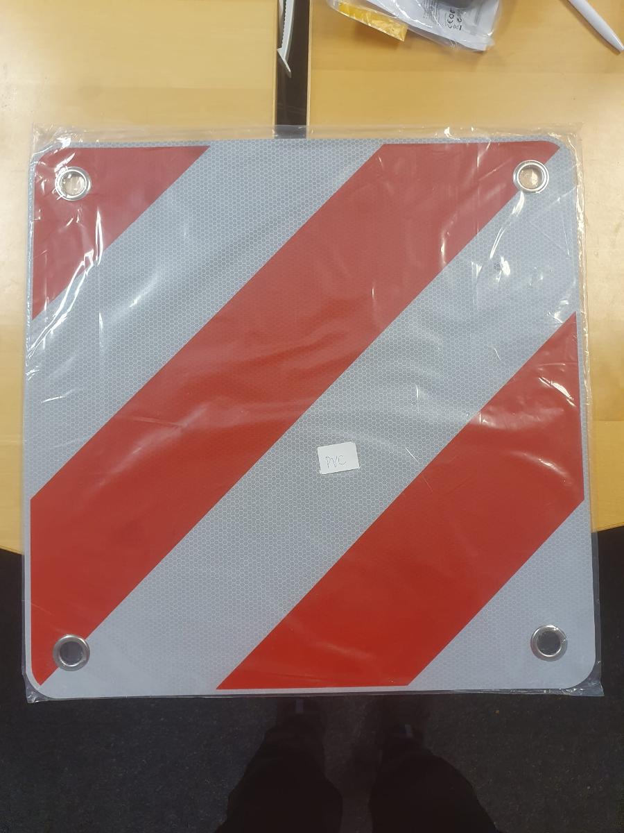 Es handelt sich um eine quadratische Tafel (Abmessungen: etwa 50 x 50 cm mit abgerundeten Ecken), bestehend aus einer PVC-Platte, die mit einer reflektierenden Folie aus Kunststoff beklebt und mit roten diagonalen Streifen bedruckt ist. Die Ecken sind gelocht und mit Ösen aus unedlem Metall verstärkt. Üblicherweise wird die Ware im Bereich des Straßenverkehrs als Warntafel zur Kennzeichnung von Ladung verwendet. Dazu kann sie z. B. an Wohnwagen, Anhängern und Fahrradträgern angebracht werden.

Aufgrund des universellen Einsatzortes und der fehlenden Erkennbarkeit kommt eine Einreihung in den ABS XVII als Teil oder Zubehör für ein Beförderungsmittel nicht in Betracht.

Abbildung siehe Anlage.

Derartige Waren gehören als "andere, als in den vorgenannten Unterpositionen genannte Drucke" zum TARIC-Code 4911 99 00 00.