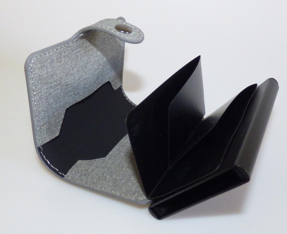 Kreditkartenetui, sog. Credit-Card Safe Etui, Foto siehe Anlage,
- mit einer flächenmäßig überwiegenden Außenseite aus gewebeartig geprägten Kunststofffolien
  (sog. Leineneinband; charakterbestimmend),
- mit einem Korpus aus unedlem Metall, der an drei Schmalseiten die Außenseite des Etuis bildet,
- mit einer Überschlaglasche mit Druckknopfverschluss,
- - zweiteilig aufklappbar; an der Innenseite des Einbands mit einer gefalteten Einsteckvorrichtung
    aus Kunststofffolie für Geldscheine, zwei offenen Einsteckfächern im Kreditkartenformat und
    einem aus unedlem Metall gearbeiteten Korpus, der passgenau zum Einstecken von Kreditkarten
    gearbeitet und an der Unterseite mit einem Ausgabemechanismus zum Auswurf der Kreditkarten
    versehen ist,
- laut Antrag mit einem RFID-Ausleseschutz,
- mit den Abmessungen: ca. 9,5 cm (Höhe) x 6,5 cm (Breite) x 2 cm (Tiefe).

"Ähnliches Behältnis (Kreditkartenetui), Taschen- oder Handtaschenartikel, mit Außenseite aus
 Kunststofffolien"