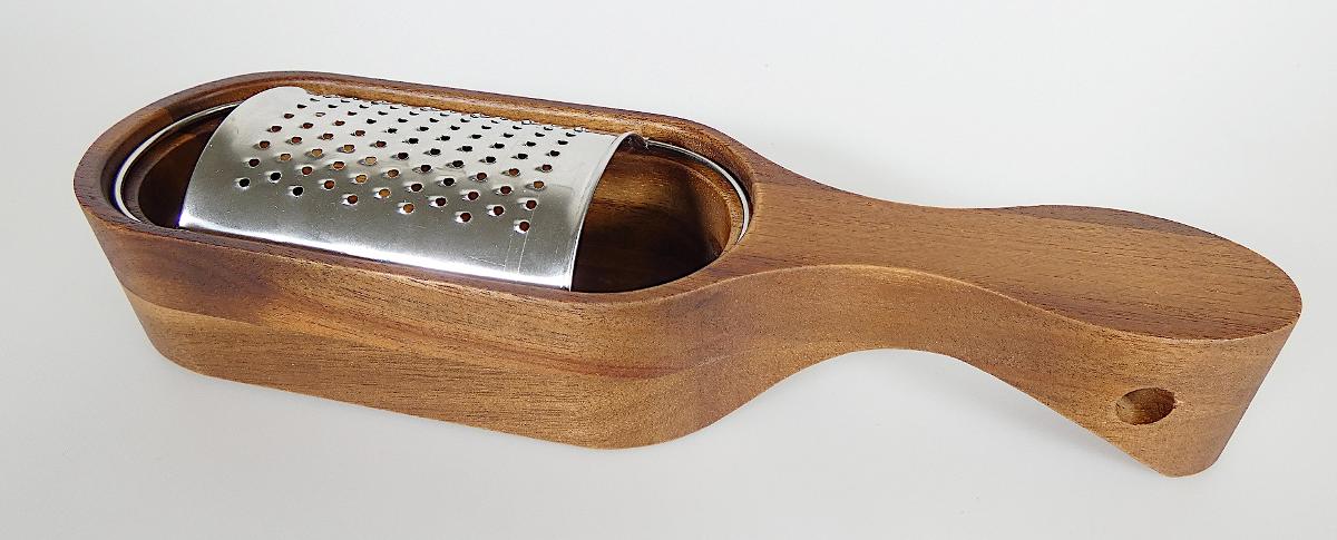 "Käsereibe"

mit freiem Arm zu handhabendes, aus verschiedenen Bestandteilen zusammengesetztes 
Erzeugnis, bestehend aus

- einem annähernd quaderförmigen Auffangbehälter, vollständig aus Holz, an einem Ende über
  die gesamte Breite verrundet und am anderen Ende zu einem Handgriff mit Öse ausgearbeitet;
  die Behälteröffnung ist mit einer innenliegenden, rundum laufenden Nut versehen

- einer feinzahnigen, gewölbten Reibfläche aus Stahl, die mittels eines rundum laufenden
  Drahtbügels aus unedlem Metall passgenau in die Nut des Holzbehälter eingesetzt ist

- Abmessungen: etwa 24﻿,﻿7 x 7﻿,﻿0 x 4﻿,﻿0 cm

- zum Reiben und Auffangen von Käse

- mit einer bedruckten Banderole versehen

- die Reibe bestimmt im Hinblick auf die Bedeutung für die Verwendung den Charakter der
  zusammengesetzten Ware

Abbildung siehe Anlage.

Derartige Erzeugnisse gehören als "Handwerkzeuge (Haushaltswerkzeuge), anderweit
weder genannt noch inbegriffen, mit arbeitendem Teil aus unedlem Metall" zum TARIC-Code
8205 5100 00.