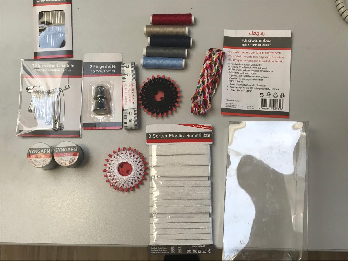 Nähgarnset, sog. Kurzwarenbox, Foto siehe Anlage,
- Warenzusammenstellung, bestehend aus neun Nähgarnen, einem Geflecht, drei Gummilitzen,
  27 Nadeln, einem Maßband und zwei Fingerhüte,
- gemeinsam in einer Kunststoffbox mit einem bedruckten Papiereinleger für den Einzelverkauf
  aufgemacht und zur Befriedigung eines speziellen Bedarfs zusammengestellt,
- Nähgarne:
-- zwei sog. Sternzwirne (laut Antrag 20 m lang), fünf sog. Syngarn-Allesnäher (laut Antrag 50 m lang) 
   und zwei sog. Nähmaschinen-Syngarne (laut Antrag 100 m lang):
--- jeweils auf einer Unterlage (Sternkarte bzw. Spule) aufgemacht, mit einem Gewicht einschließlich der
    Unterlage von ca. 2,4 g bis ca. 9,5 g (= Garn in Aufmachung für den Einzelverkauf),
--- gefärbte sowie gebleichte Garne aus synthetischen Spinnfasern (laut Antrag Polyester),
--- gezwirnt, mit einer Z-Drehung als letzter Drehung,
--- appretiert für die Verwendung als Nähgarn,
- Geflecht, sog. Nähgarnzopf:
-- als Meterware; mit einer Länge von ca. 45 cm und einer Breite von ca. 2 cm,
-- aus einem Flachgeflecht aus Garnen aus synthetischen Spinnfasern (laut Antrag Polyester),
- Gummilitzen:
-- als Meterware; mit einer Breite zwischen 6 mm und 13 mm,
-- aus ca. 1 mm dicken, einfarbigen Gewirken aus laut Antrag 55 GHT bis 57 GHT Polyester
   (synthetische Chemiefasern) und 43 GHT bis 45 GHT Kautschukfäden,
-- keine Elastomergarne enthaltend,
-- ohne Flor- oder Schlingenoberfläche,
- Nadeln:
-- 15 Sicherheitsnadeln aus unedlem Metall,
-- zwölf Nähnadeln aus unedlem Metall,
- Maßband; mit einer Länge von laut Antrag 150 cm,
- Fingerhüte:
-- mit einem Durchmesser von ca. 16 mm bzw. 18 mm,
-- aus unedlem Metall,
- die Nähgarne aus synthetischen Spinnfasern bestimmen insbesondere im Hinblick auf den Umfang
  und die Bedeutung in Bezug auf die Verwendung den Charakter der Warenzusammenstellung.

"Nähgarne aus synthetischen Spinnfasern, in Aufmachung für den Einzelverkauf"