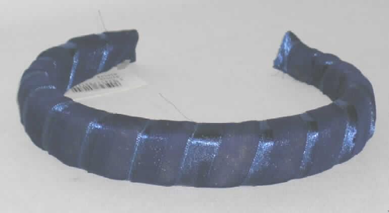 Haarspangenähnliche Ware aus Kunststoff, in Form eines Haarreifs.
Es handelt sich um einen Haarreif, der aus einem ca. 2,5 cm breiten, gebogenen, der Kopfform angepassten, an den Enden offenen Kunststoffreif besteht. Der Reif ist auf der Oberseite mit Schaumstoff versehen und vollständig mit blaufarbenen Spinnstoffbändern umwickelt. Der Kunststoff bildet aufgrund des Umfangs sowie seiner Bedeutung hinsichtlich des hauptsächlichen Verwendungszwecks der Ware (Zusammenhalten des Haares) den charakterbestimmenden Stoff.
Ein Bild der Ware ist im Internet unter http://ec.europa.eu/taxation_customs/dds/ebticau_de.htm
zu finden.