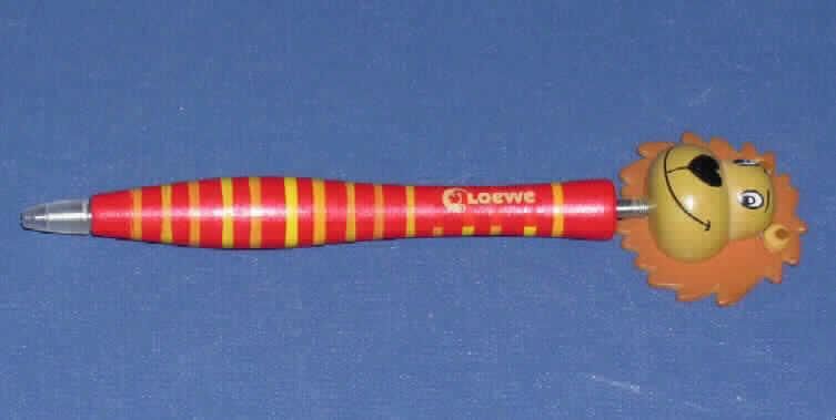 Kugelschreiber mit nicht auswechselbarer Mine, die mit pastöser (nicht flüssiger) Tinte gefüllt ist, als zusammengesetzte Ware mit einer Schutzkappe aus Kunststoff und einem stilisierten Löwenkopf aus bemaltem Holz, der mittels einer Feder am oberen Ende des Kugelschreibers befestigt ist. Der Kugelschreiber bestimmt hinsichtlich des Umfangs und der Verwendung den Charakter der zusammengesetzten Ware und besteht aus einem Gehäuse aus Holz (Maße: 10 x 0,8 cm = L x D), das sich auf Fingerhöhe verdickt und in dessen unterem Ende eine Schreibspitze mit fest integrierter Mine eingeschoben ist. Das Gehäuse ist bunt bemalt und trägt die Aufschrift "Löwe" mit einem Löwen-Logo. 
Der Kugelschreiber ist in einer klarsichtigen Kunststofftüte verpackt.

Abbildung im Internet unter:
http://ec.europa.eu/taxation_customs/dds/ebticau_de.htm
.