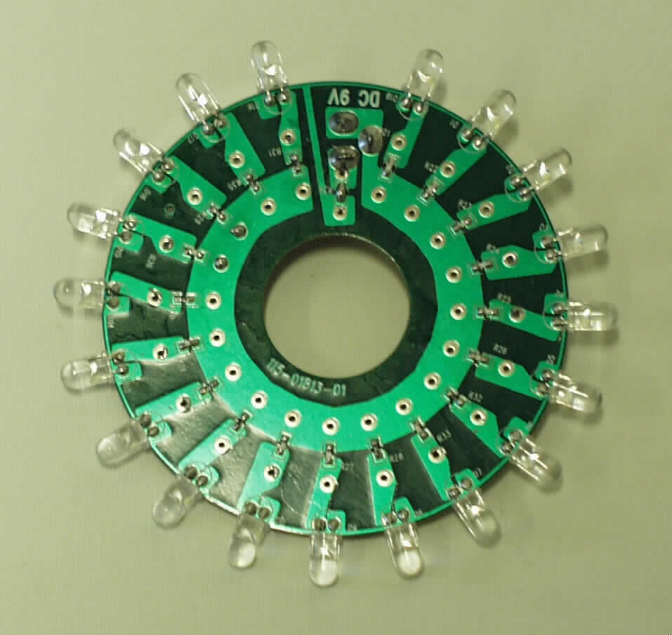 Erkennbares Teil eines elektrischen Beleuchtungskörpers (Kinderlampe "Käfer"),
nicht handgearbeitet, im Wesentlichen bestehend aus einer runden, ca. 8 cm großen Platine, die mit insgesamt 19 Leuchtdioden (davon 7 gelbe, 6 blaue und 6 grüne) und einem Adaptoranschluss (DC 9 V) ausgestattet ist.

Die Platine ist nicht handgearbeitet. Sie dient zum Einbau in eine elektrische Kinderlampe "Käfer" und stellt die Lichtquelle dar.