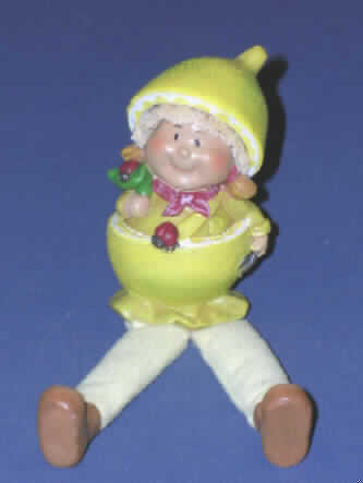 Puppe, die Nachbildung eines Menschen darstellend, keine handgearbeitete dekorative Puppe in für das Ursprungsland charakteristischer Volkstracht, sog. "Früchtefigur".

Die Figur stellt eine ca. 17 cm große Nachbildung eines Mädchens mit beweglichen, aus Spinnstoff bestehenden und mit weichem Material gefüllten Beinen dar. Kopf, Rumpf, Arme und Füße bestehen aus Steinharz.
Das Mädchen ist als Zitrone verkleidet. Es hat ein rotes Halstuch, ein gelbes Oberteil und die untere Hälfte einer Zitrone an und trägt die obere Hälfte der Zitrone als Kopfbedeckung, unter der die z.T. aus Stroh bestehenden, zu zwei Zöpfen frisierten Haare hervorlugen. Auf der rechten Schulter des Mädchens und der unteren Zitronenhälfte sitzt jeweils ein Marienkäfer. In der rechten Hand hält die Figur einen heckenscherenähnlichen Gegenstand.

Es handelt sich um eine Dekorations-/Zierpuppe in Form eines Kantenhockers, der z.B. auf eine Tischecke gesetzt werden kann, so dass die Beine beweglich herunterhängen.

Ein Bild der Ware befindet sich im Internet unter: http://europa.eu.int/comm/taxation_customs/dds/de/ebticau.htm.
