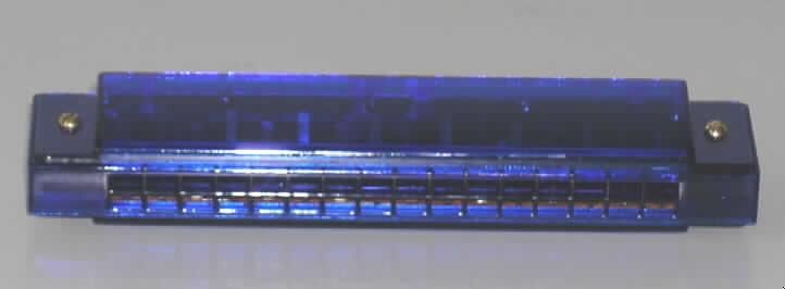 Blasinstrument in Form einer Mundharmonika, Länge 130 mm, bestehend aus einem Kanzellenkörper aus Kunststoff mit 16 Blasöffnungen (Kanzellen) für 16 Töne. Die Mundharmonika ist in einer bedruckten Pappschachtel verpackt.