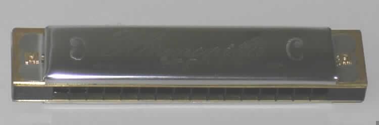 Blasinstrument in Form einer Mundharmonika, Länge 130 mm, bestehend aus einem Kanzellenkörper aus Kunststoff und Stahlblecheinfassungen, mit 16 Blasöffnungen (Kanzellen) für 16 Töne. Die Mundharmonika ist in einer bedruckten Pappschachtel verpackt.