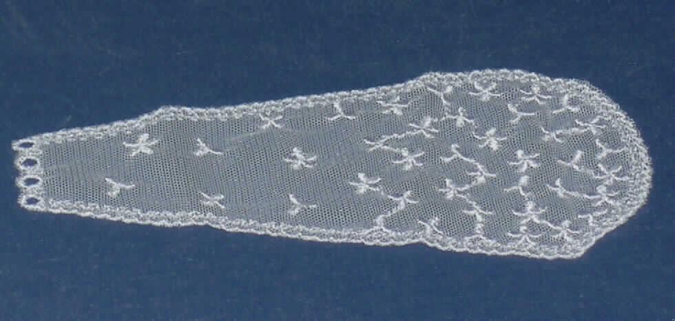 Zubehör für eine Puppe, ein menschliches Wesen darstellend, sog. Brautschleier für Spielzeugpuppen.
Es handelt sich um Zubehör, erkennbar für eine Puppe in Form eines ca. 16 cm langen, am unteren Ende oval geformten, weißen Schleiers aus netzartig gestaltetem Spinnstoffmaterial (Baumwolle und Nylon lt. Antrag) mit aufgestickten Blüten und besticktem Rand. Am oberen Ende weist das Erzeugnis vier runde Aussparungen zur Befestigung an einem Kunststoffblütenkranz (nicht Gegenstand dieser Auskunft) für die Puppe auf. 
Der Schleier dient der spielerischen Unterhaltung von Kindern.
Ein Bild der Ware ist im Internet unter http://ec.europa.eu/taxation_customs/dds/ebticau_de.htm zu finden.