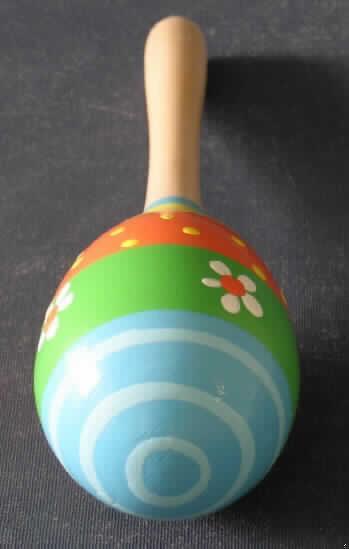 Schlaginstrument (Maraca, Art.-Nr. 802528), bestehend aus einem mit kleinen Klangstücken (Pflanzensamen, Schrot oder Kieselsteine) gefüllten, ovalen Klangkörper aus lackiertem Holz, mit Griff (Länge ca. 20 cm), womit durch Schütteln einen Ton erzeugt wird.