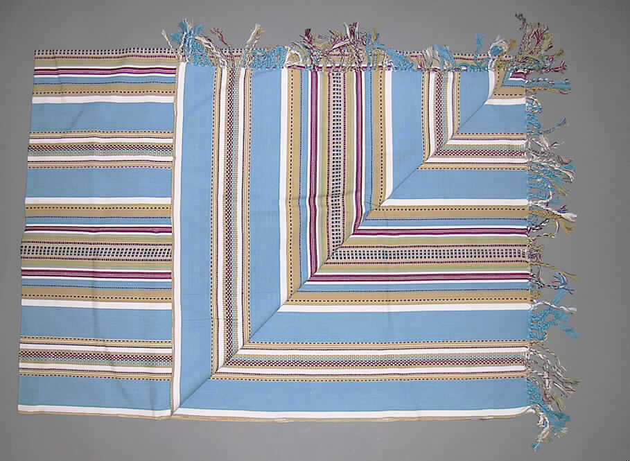 Decke, sog. Decke Marokko (Art. 55432), siehe Foto,
- aus 0,8 mm dicken, buntgewebten Geweben aus lt. Antrag 100% Baumwolle,
- rechteckig, in den Abmessungen von etwa 180 cm x 130 cm,
- an den Längsseiten mit echter Webkante, an den Schmalseiten durch 10 cm lange, geknüpfte Fransen 
  aus den Fäden des Gewebes befestigt (somit konfektioniert),
- lt. ergänzenden Antragsangaben nicht handgearbeitet,
- ohne elektrische Heizvorrichtung,
- kennzeichnet sich nach Material, Ausstattung und Abmessung als Decke, die im Haus oder auf Reisen 
  verwendet wird (somit kein Bettüberwurf der Position 6304).