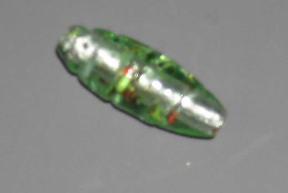 Glasperle, siehe Foto, 
- ovale, spiralförmig gedrehte, massive Perle aus vollständig durchbohrtem Glas, 
- - überwiegend grün mit Folieneinzug (lt. Antrag), 
- mit einer Länge von ca. 35 mm und einem Durchmesser von ca. 12 mm, 
- nicht geschliffen und mechanisch poliert, da die Perle weder glatte und scharfkantig abge- 
  grenzte Schleifflächen (Facetten) noch einen geschliffenen Lochrand aufweist, 
- keine Nachahmung von echten Perlen, Zuchtperlen, Edel-, oder Schmucksteinen, 
- zum Herstellen von z.B. Halsketten u.ä. bestimmt, 
- augenscheinlich nicht handgearbeitet.