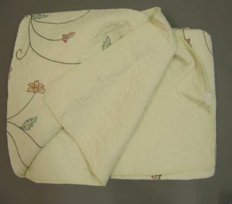 Ware zur Innenausstattung (Bettüberwurf), sog. Patchwork Plaid (Art.Nr. 880473), 
siehe Foto,
- rechteckig, mit abgerundeten Ecken; in den Abmessungen von etwa 205 cm x 150 cm,
- aus einem ca. 4,0 mm dicken, dreilagigen, abgeteilt versteppten Flächenerzeugnis der
  Position 5811 mit einer Außenlage aus einer Stickerei der Position 5810 mit einem
  Stickgrund aus Geweben aus laut Antrag 100% Baumwolle, einer bis zu 3 mm dicken
  Zwischenlage aus Wattierungsstoff und einer Innenlage aus einfarbigen Geweben aus laut
  Antrag 100% Baumwolle,
- an allen Rändern mit einem Streifen aus Geweben eingefasst (somit konfektioniert),
- kennzeichnet sich insbesondere aufgrund der Gestaltung der Oberseite, des Materials
  (dreilagiges, relativ steifes Flächenerzeugnis) und den Abmessungen als Bettüberwurf,
  somit keine Decke der Position 6301,
- aufgrund der geringen Polsterung keine Bettausstattung der Position 9404.