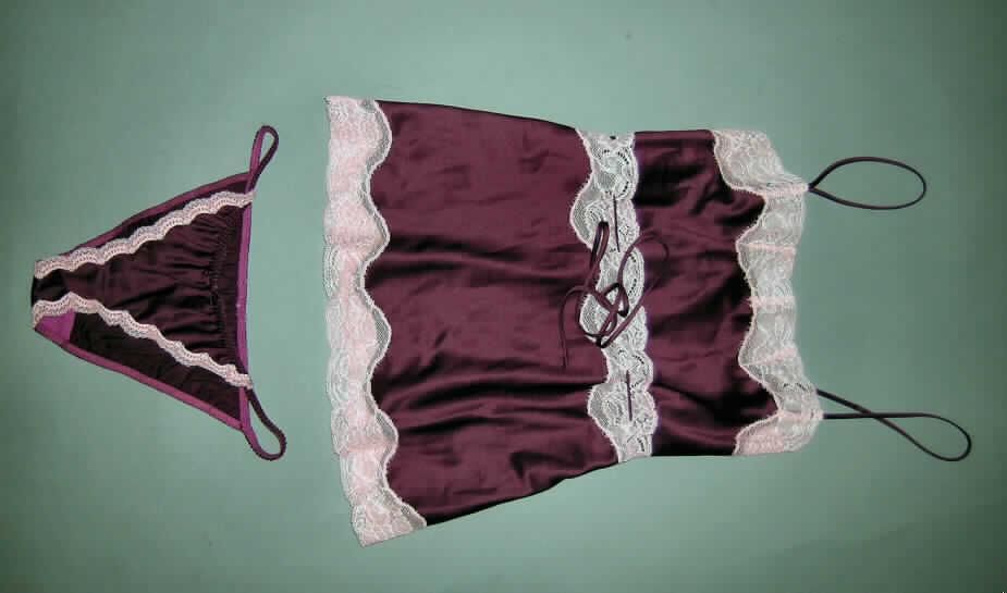 Zweiteilige Zusammenstellung, bestehend aus einer Bluse und einem Slip für Frauen, sog. 
2tlg. Wäschegarnitur, Größe 34/36, siehe Fotos,
- in gemeinsamer Aufmachung für den Einzelverkauf,
- keine Kombination, u.a. weil ein Slip als Bestandteil einer Kombination nicht zugelassen ist,
- aus 0,3 mm dicken, leichten, einfarbigen, glänzenden Satingeweben aus lt. Antrag 100 % 
  Polyester (synthetische Chemiefasern), 
- Slip für Frauen: 
-- in Form eines Tangaslips gearbeitet,
-- aufgrund des Schnitts eindeutig als Frauenkleidung erkennbar,
-- in der Taille abschließend, mit einem elastisch gearbeiteten Taillenbund,
-- mit sehr hohen Beinausschnitten, 
-- ohne Öffnung und ohne Verschluss, 
-- im Schritt mit einer Hygieneeinlage gearbeitet,
-- im Vorderteil an den Seitenrändern mit angenähten Zuschnitten aus kontrastfarbenen, 
   durchbrochenen Gewirken (sog. Raschelspitze) verziert.