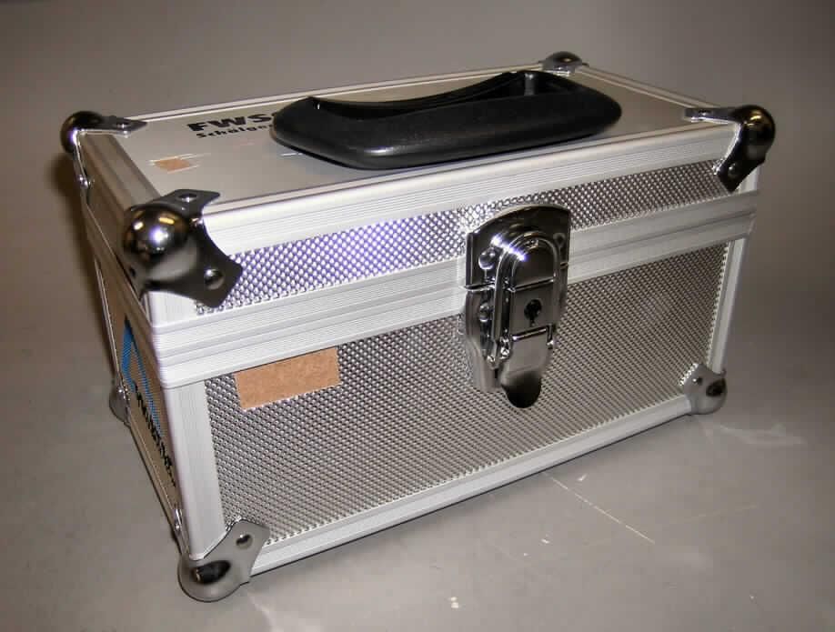 Handkofferähnliches Behältnis, sog. Transportkiste für ein Schälgerät, siehe Fotos, 
- mit einer Außenseite aus Aluminium, welches auf einer Unterkonstruktion aus entspre- 
  chend zugeschnittenen Holzfaserplatten aufgeklebt ist, 
- mit einem Kantenschutz aus Aluminiumprofilen und Kugeleckbeschlägen aus unedlem 
  Metall, 
- mit den Innenabmessungen von ca. 23,5 x 12 x 12,5 cm, 
- mit einem Handtragegriff aus Kunststoff auf dem Deckel, 
- mit einem abschließbaren Bügelschloss aus unedlem Metall, 
- innen mit Schaumkunststoff mit speziell geformten Aussparungen ausgekleidet, 
- zum Transport eines Schälgerätes vorgesehen.