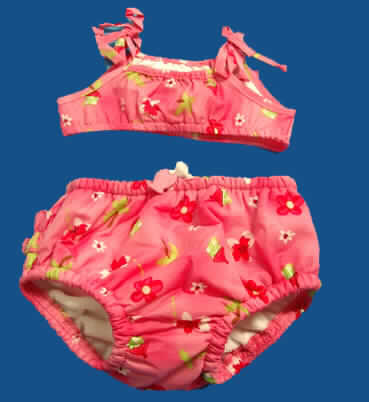 Kleidung für Kleinkinder, sog. Bikini mit Windeleinsatz, Art. IP 221, für Kleinkinder bis 
18 Monate), s.Abb.;
- als zweiteiliger Badeanzug (sog. Bikini) in einem gemeinsamen Polybeutel mit Bügel
  für den Einzelverkauf aufgemacht,
- charakterbestimmend aus 0,2 mm dicken, bedruckten Geweben aus (lt. Etikett) 
  100% Nylon (Polyamid / synth. Chemiefasern),
- Oberteil:
-- mit Trägern über den Schultern zu binden,
-- die Brust bedeckend,
-- mit einem elastischen Abschluss am unteren Rand,
-- im Vorderteil mit einem Gewirke unterlegt,
-- am oberen Rand mit einem aufgesetzten, gerüschten Streifen,
- Unterteil:
-- in der Taille abschließend, mit elastischem Bund und Zugkordel,
-- mit einem Futter aus einfarbigen Schlingengewirken, die einseitig mit einer Lage 
   Kunststoff versehen sind,  aus lt. Etikett 100 % Polyester (Meterware: Pos. 6001),
-- mit enganliegenden, elastischen Abschlüssen an den Beinausschnitten.