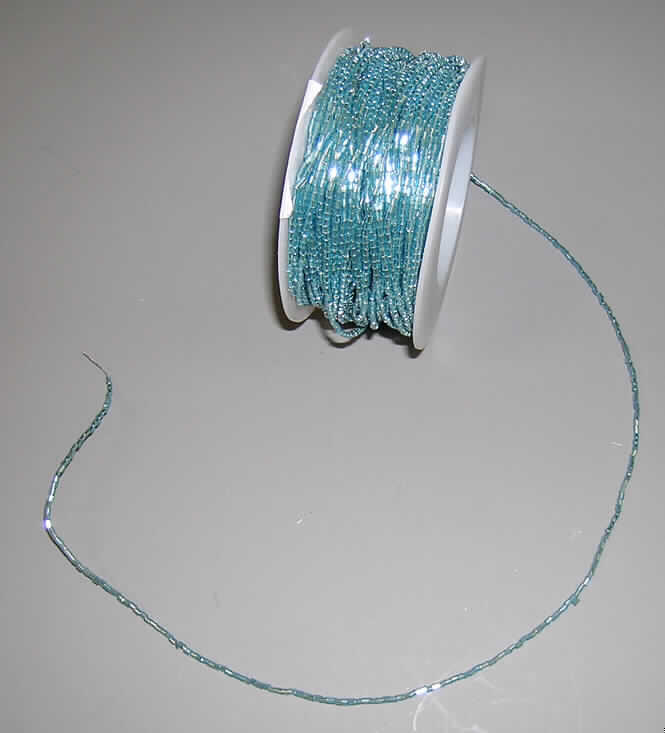 Erzeugnis aus Glaskurzwaren, sog. "Kristalldraht" zum Basteln oder zur Dekoration, siehe Foto, aus verschiedenen Stoffen zusammengesetzte Meterware auf Rollen, bestehend aus
- aus Glas in Form von Glasperlen in der Art von Glasröhrchen (Glaskurzwaren),
-- 2 bis 3 mm lang,
- aus unedlem Metall in Form eines dünnen Drahtes,
- die Glasperlen sind auf den Metalldraht aufgefädelt,
- die Meterware ist auf eine handelsübliche Rolle aus Kunststoff aufgebracht, 
- soll zur Dekoration oder zum Basteln verwendet werden,
- kein Fantasieschmuck der Position 7117,
- die Glasperlen (Glaskurzwaren) bestimmen nach dem Wert, Gewicht und dem äußeren 
  Erscheinungsbild den Charakter der Ware.